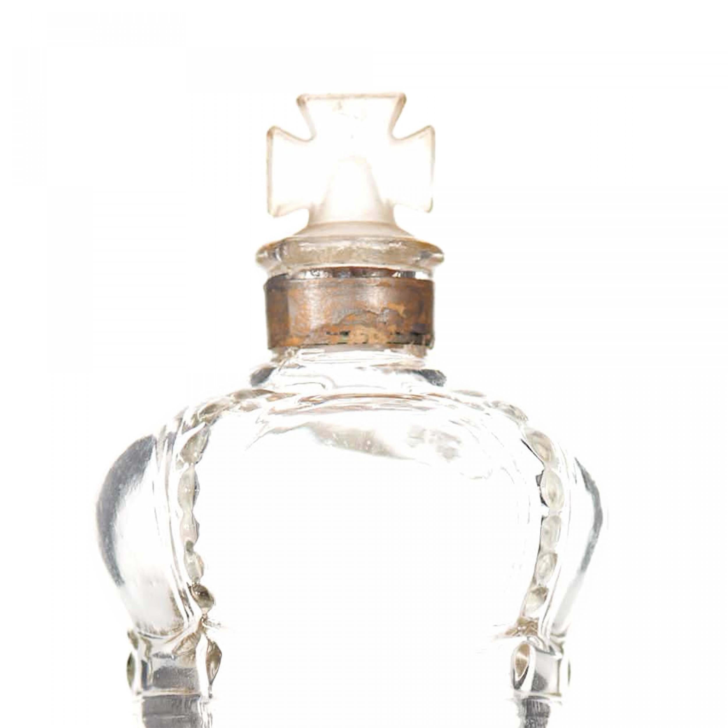 Bottiglia di profumo cilindrica in vetro trasparente Art Deco francese (DUCHESS OF YORK by PRINCE MATCHABELLI) con base svasata, sommità a forma di corona e tappo a forma di croce di Malta in vetro smerigliato.