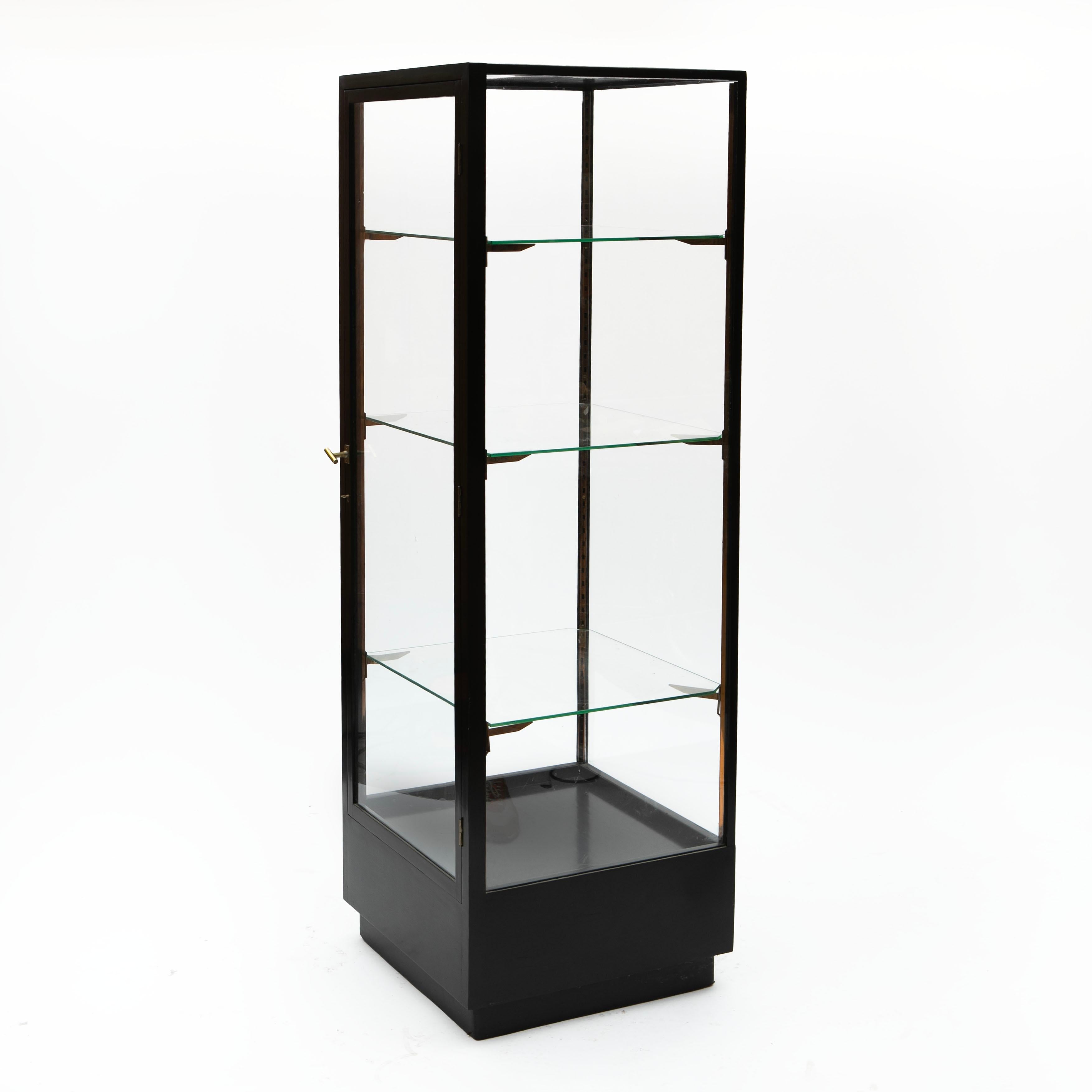 Französische Art-Déco-Vitrine aus ebonisiertem (schwarz poliertem) Holz, mit Glas auf allen vier Seiten. Der Schrank hat eine Glastür in voller Höhe mit einem Messinggriff. 
Im Inneren befinden sich drei Glasböden, die von originalen
