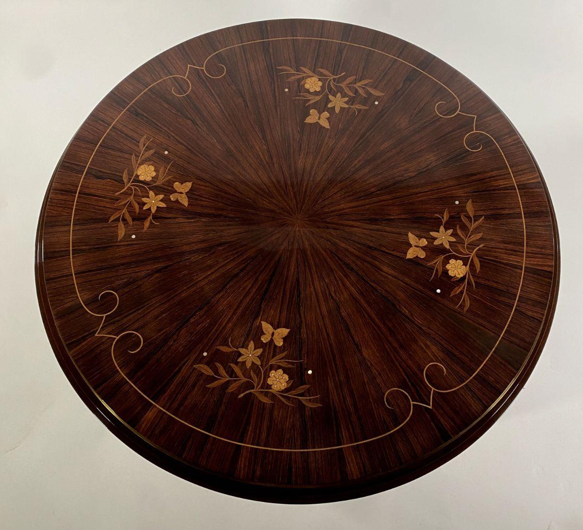 The round top, radially veneered, in ebony de macassar with intricate floral inlay, and inlaid banding, in mixed fruitwoods, on round tapering legs, with bronze bands and bronze sabots.