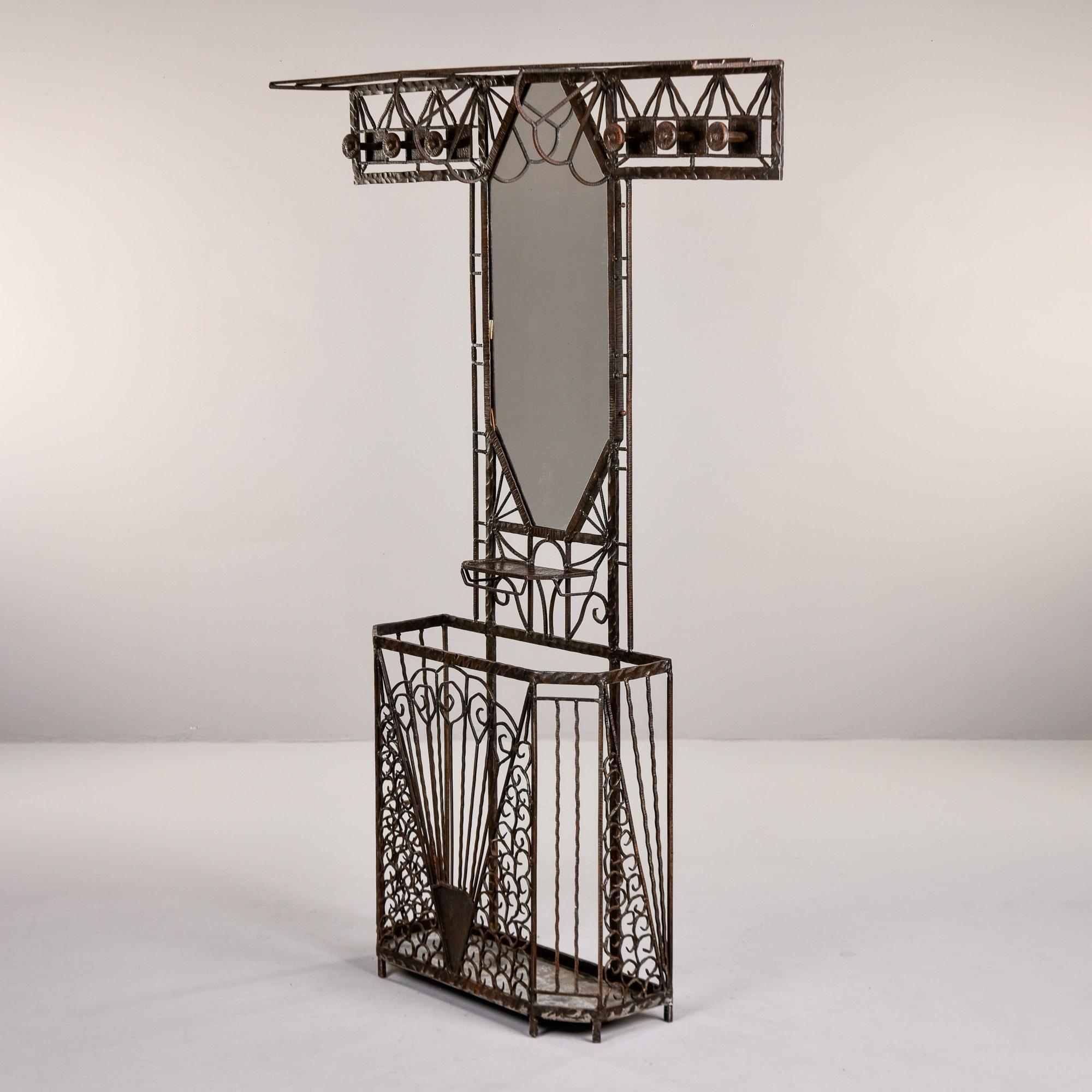 Found in France, this iron Art Deco hall stand dates from the 1930s. Forged iron work in the style of Edgar Brandt features a footed umbrella stand at the base with fan-shaped decoration on the front panel and decorated side panels. Top features an