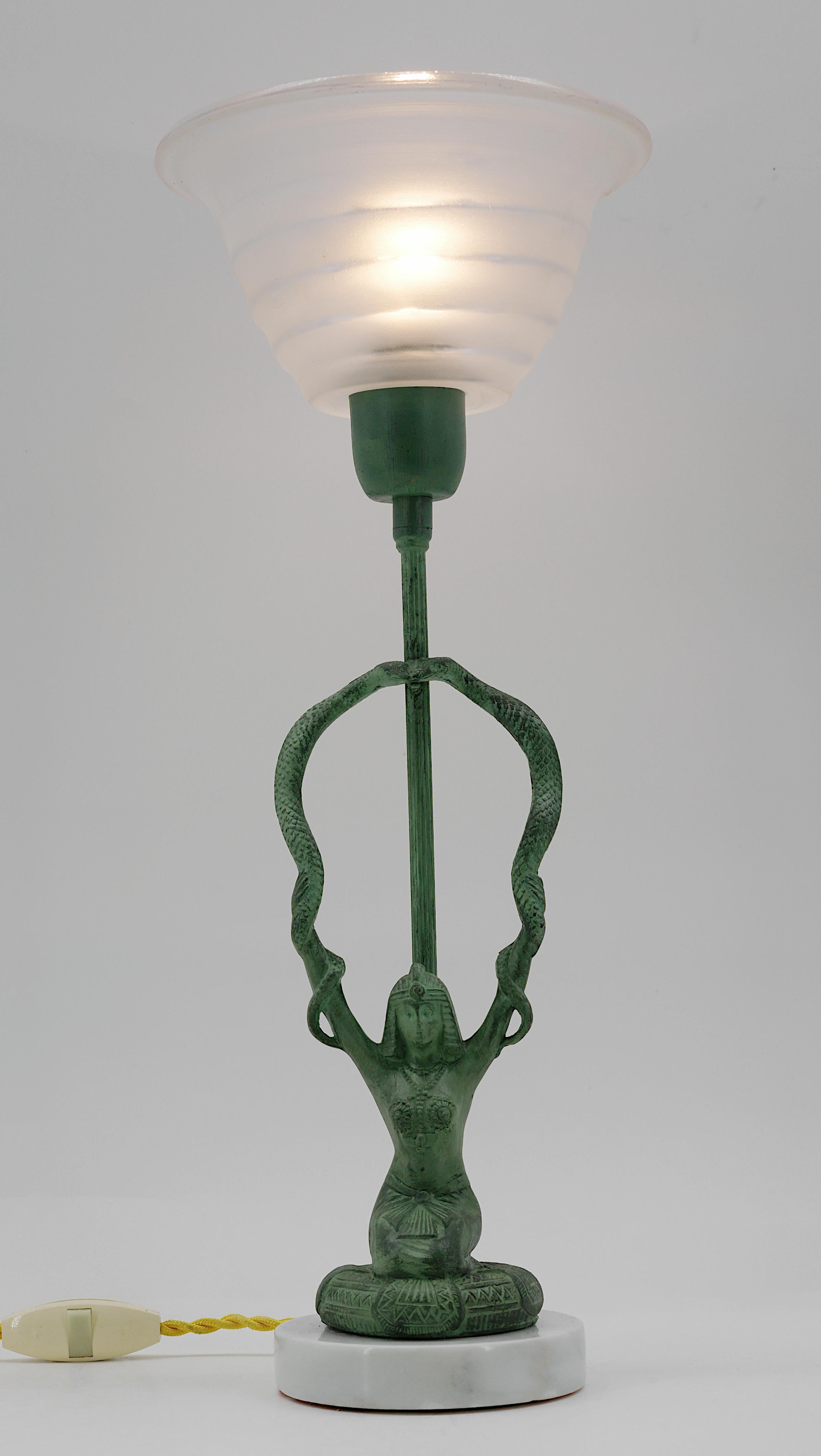 Ampoule de table Art déco française, années 1930. Femme égyptienne avec des serpents dans les bras. Fonte, verre et marbre. Abat-jour en verre de Georges Leleu (Paris). Hauteur : 40,5 cm, diamètre : 16,2 cm. Très bon état. Livré câblé pour votre