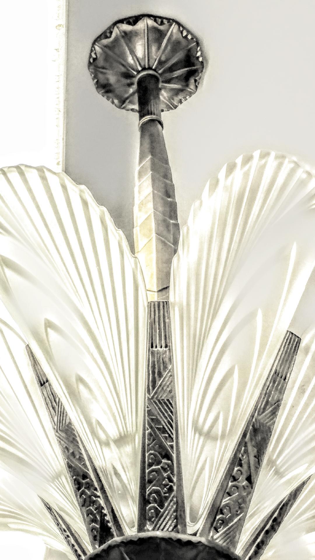 Lustre Art Déco français à huit panneaux de plumes avec des abat-jours en verre clair dépoli décorés d'un motif géométrique de plumes. Montées sur des cadres géométriques Art déco en bronze au design épuré assortis. Remplacé en nickel et recâblé aux