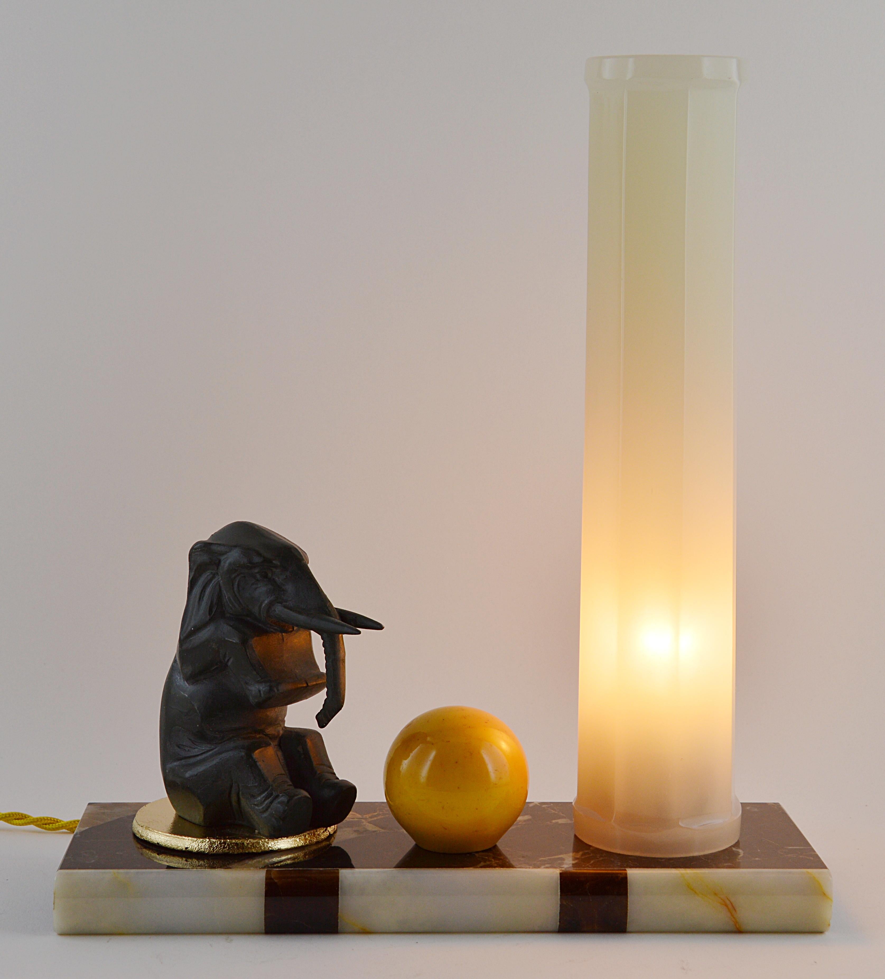French Art Deco table lamp or night-light, 1930s. Spelter elephant near a big bakelite ball. Superb thick neoclassical antique column shade. Marble and onyx base.

 