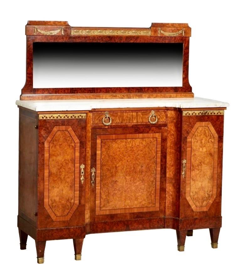 French Art Deco Eleven Piece Carved Inlaid Burled
Walnut and Ormolu Mounted Dining Room Suite, c.1930, consisting of a marble top server with a beveled mirror back splash, over a breakfront ogee edge figured creme marble above a setback center