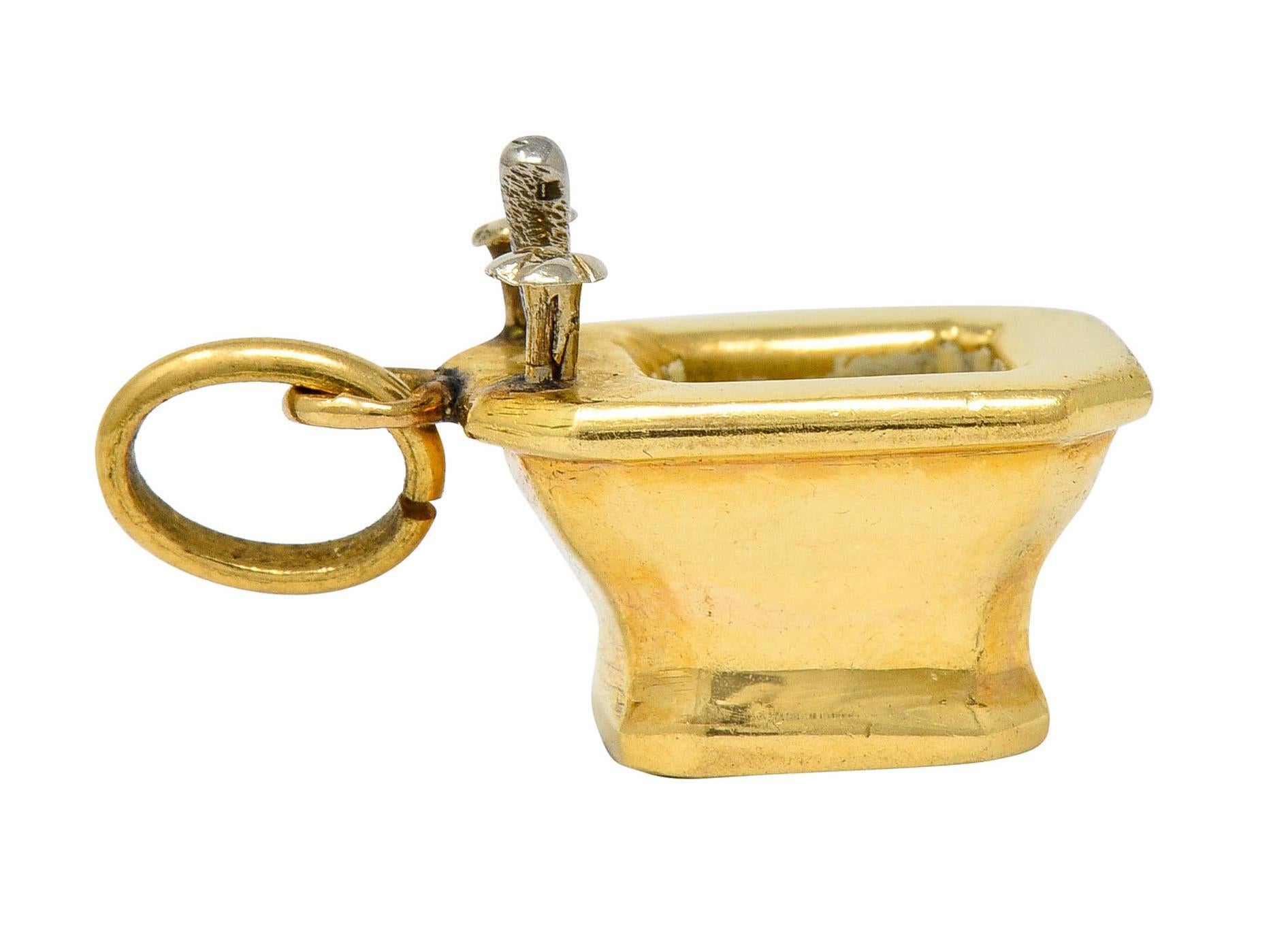 Charm is designed as a polished gold octagonal bidet with a deep cavity and white gold accents
Cavity is glossed with off-white enamel, exhibiting no loss
Completed by a jump ring bale
With French assay marks for 18 karat white gold
Circa: