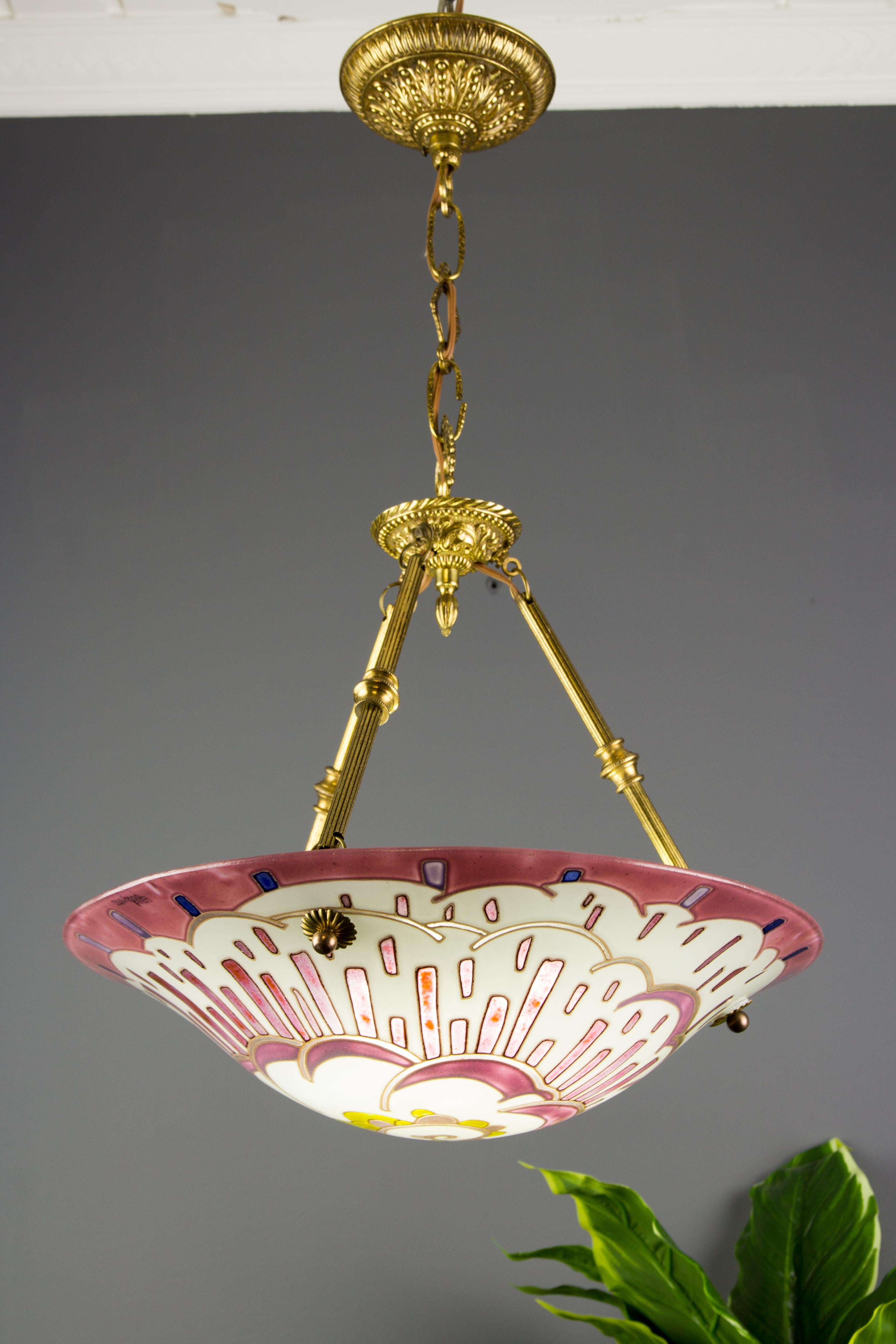 A colorful and charming Art Deco pendant light by Maxonade Verrier D’Art, Paris, with modernist geometric pattern decoration, predominately in pink, purple, yellow, brown, and blue. The drawing is hand-painted and made using enamel paint with a very