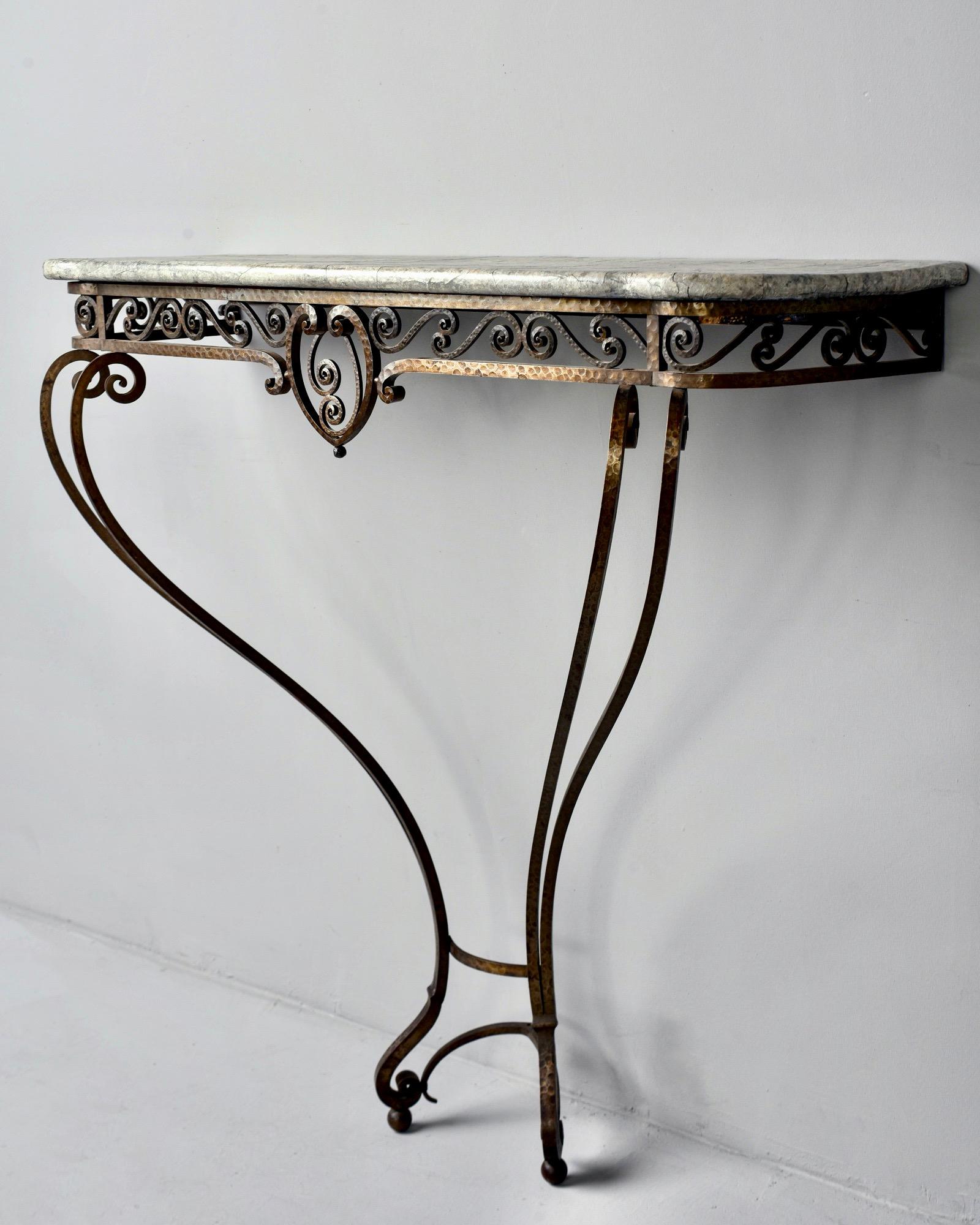 French Art Deco wall-mounted console features a hand forged, hammered iron base with lots of scroll work, circa 1930s. Top is wood with faux painted finish to mimic marble. Unknown maker.