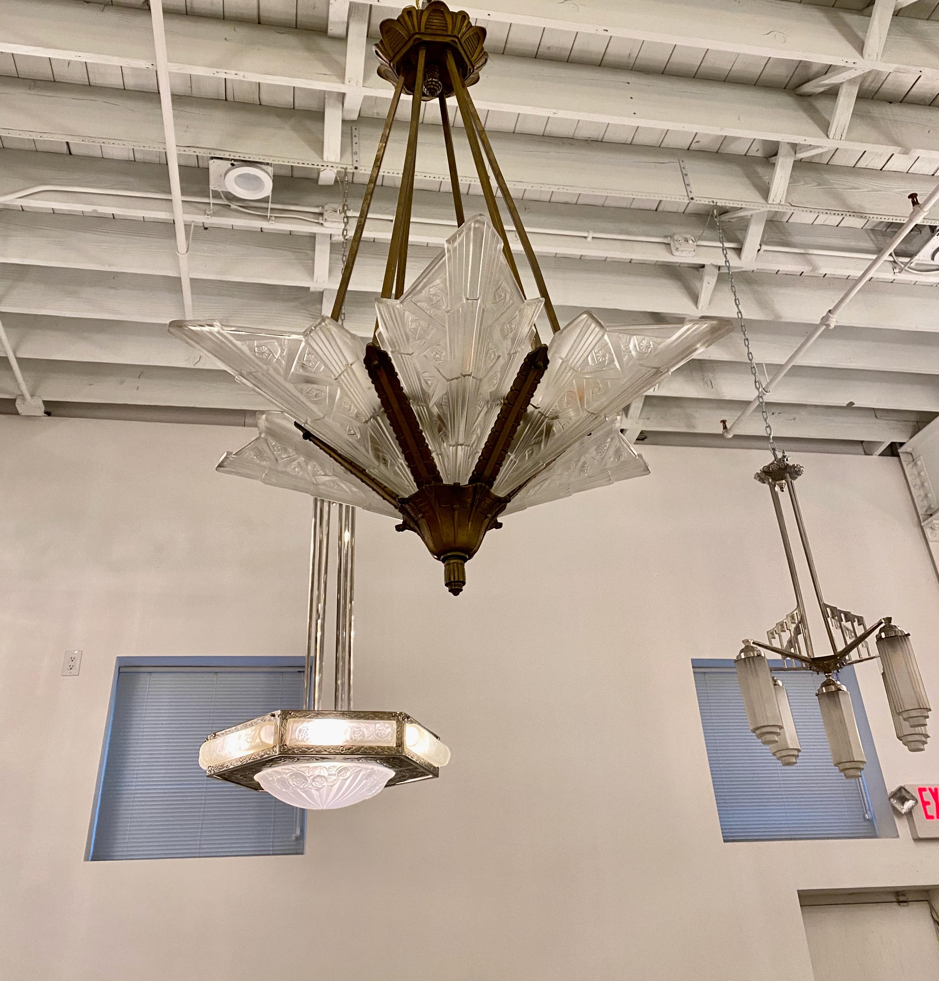 French Art Deco geometric and floral chandelier. Having six clear frosted glass panels having floral and geometric motif. The glass panels rest in a brass frame having Deco details throughout. Has been rewired for American use with six candelabra