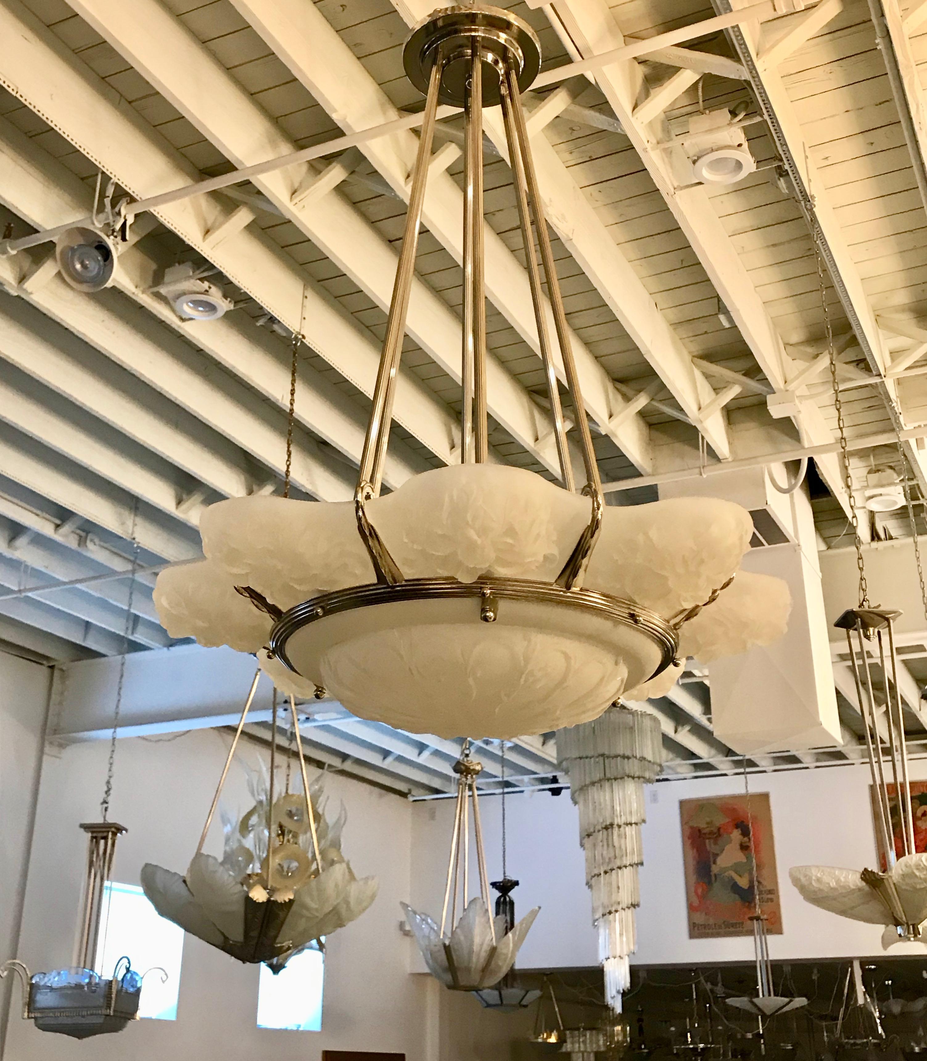 French Art Deco chandelier from the 1930s signed by Marius-Ernesto Sabino. Eight outer frosted glass panels in floral motif with center coupe. Held by a bronze nickel frame with eight ribbed rods. The frame has been re plated in polished nickel. Has