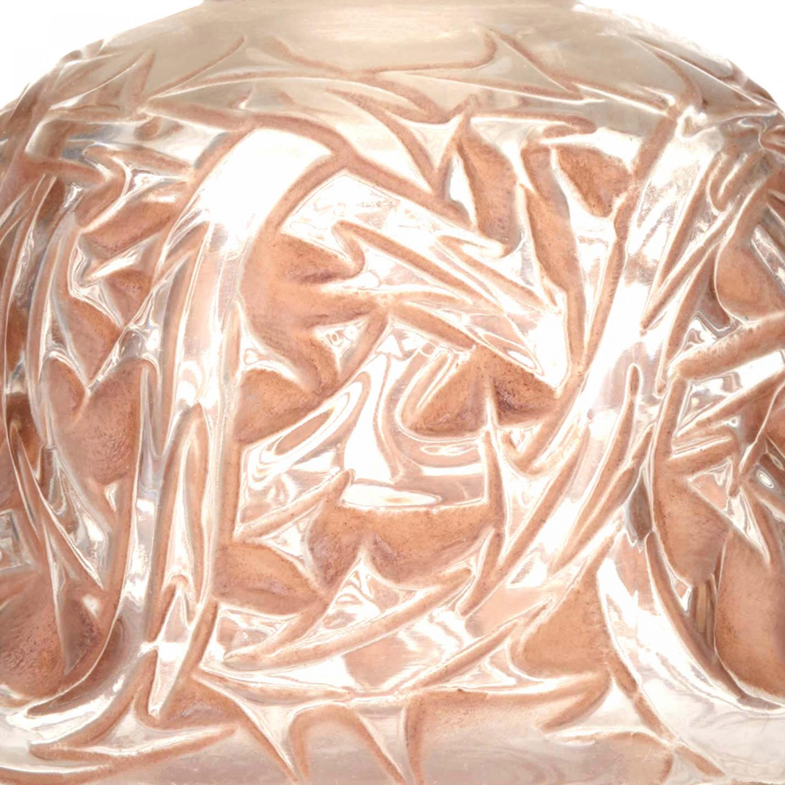French Art Deco round glass perfume bottle with decorative floral and scroll relief with a rust-colored staining (signed LALIQUE)