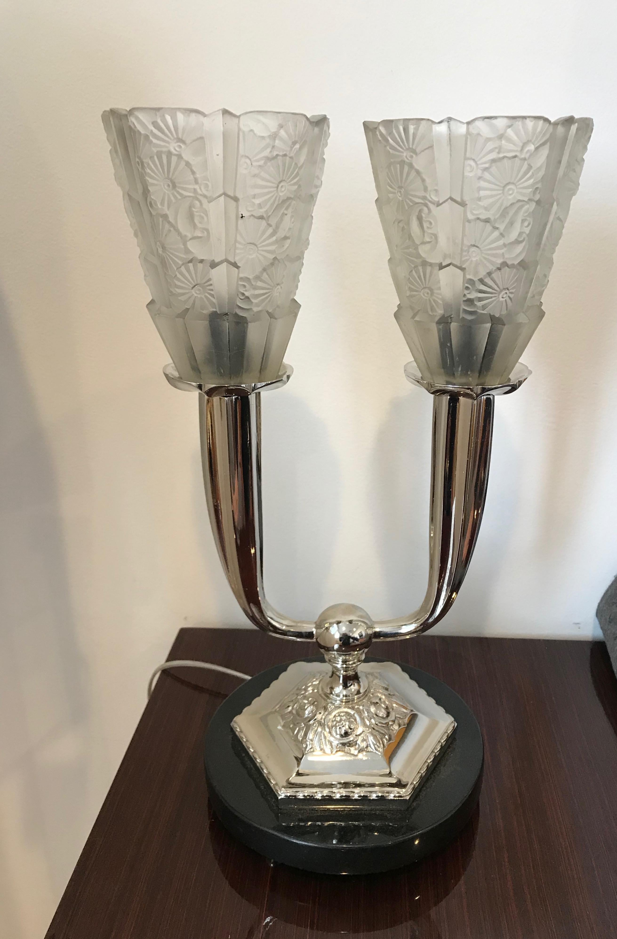 French Art Deco floral table lamp. Two clear frosted floral glass shades held by polished nickel frame sitting on black marble base. Has been re plating in polished nickel and re wired for American use. Each shade takes one candelabra socket. For a