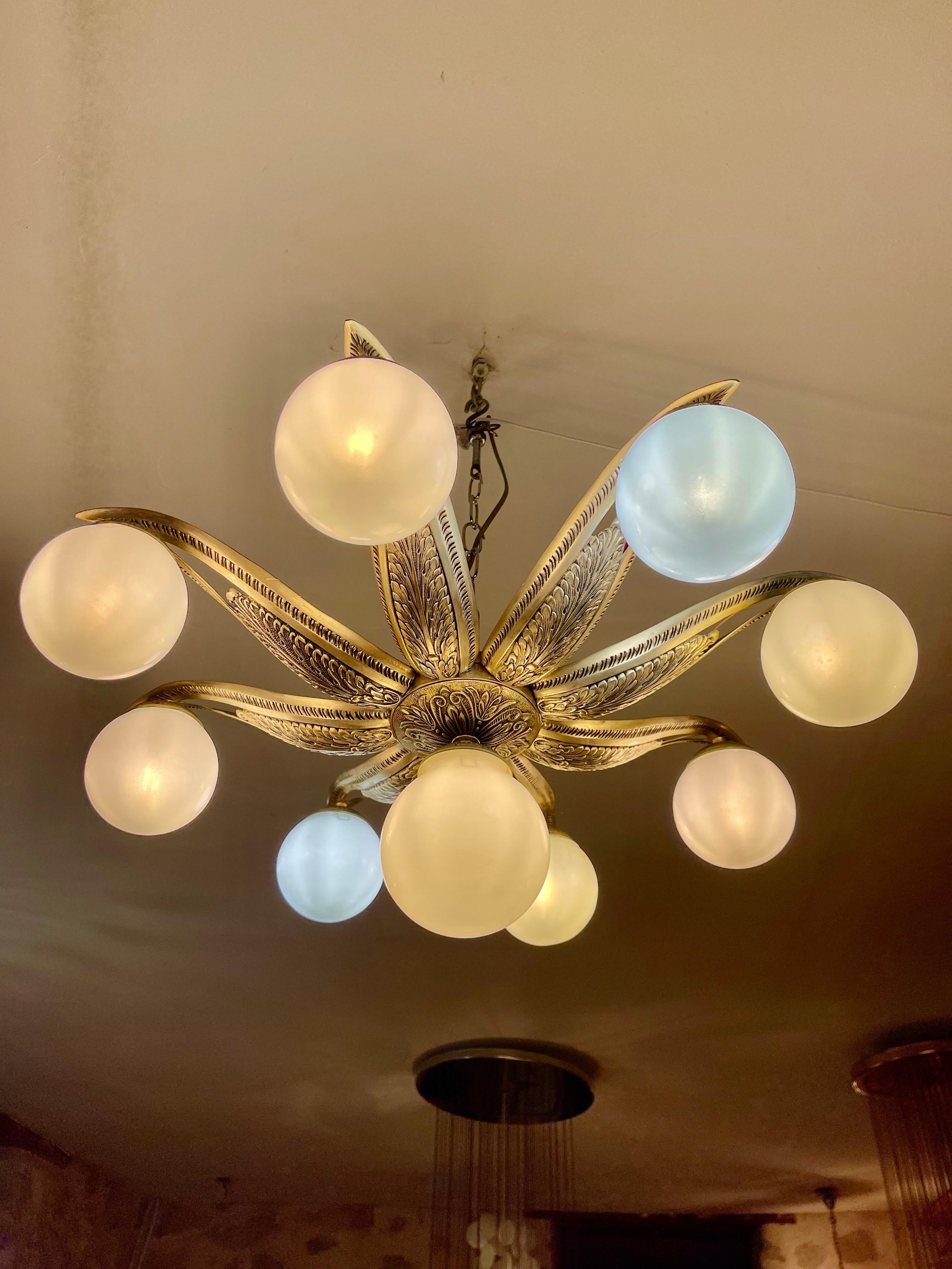Art Deco ceiling light in the shape of a flower or sun, in etched and cast bronze, with opaline milk glass. France, 1930s. This ceiling light features a stylized flower or sun motif. In the center is a beautiful opal glass globe to diffuse light.