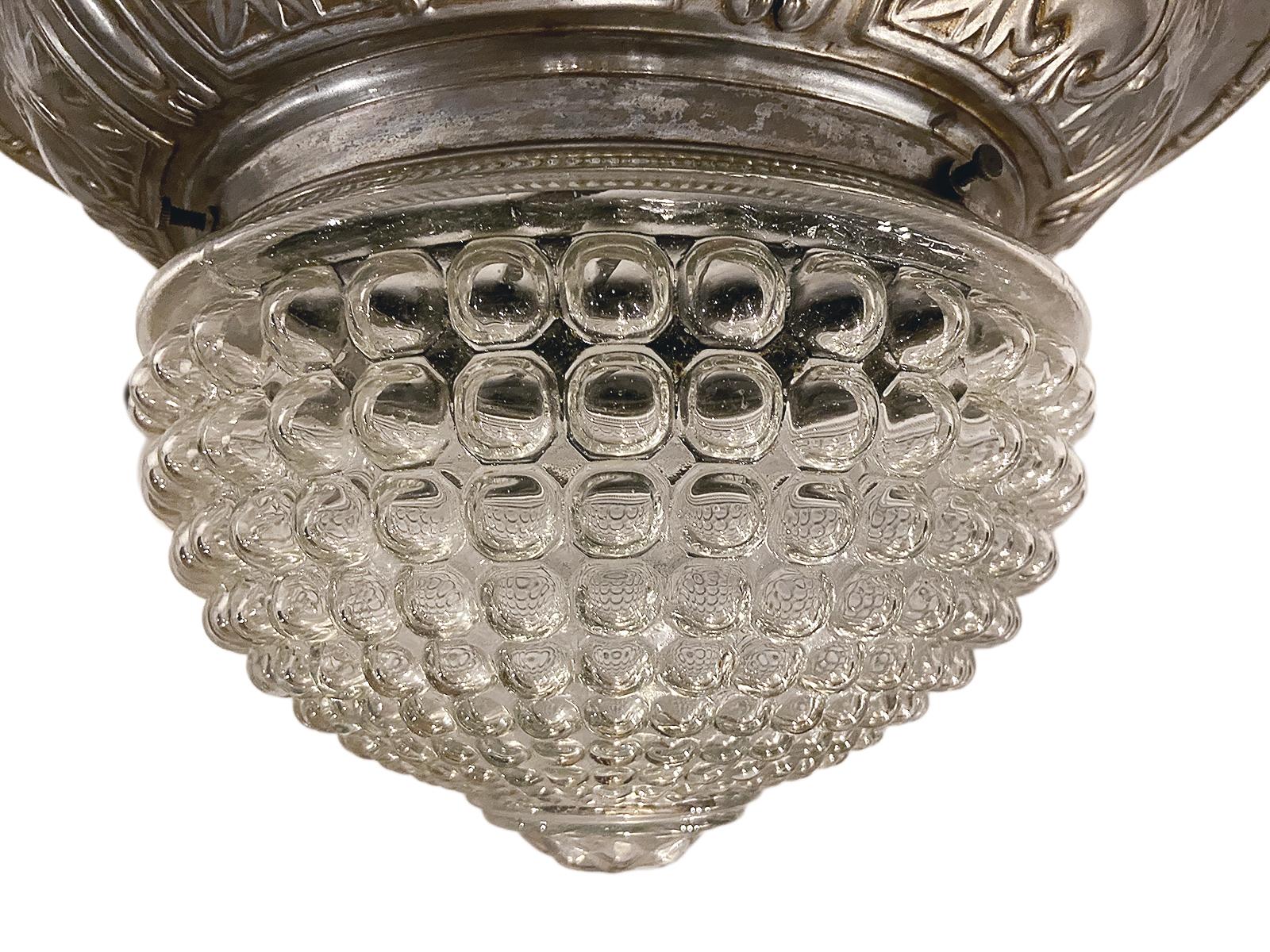 Luminaire en verre moulé français des années 1920 avec corps argenté repoussé.

Mesures :
Diamètre 14.5