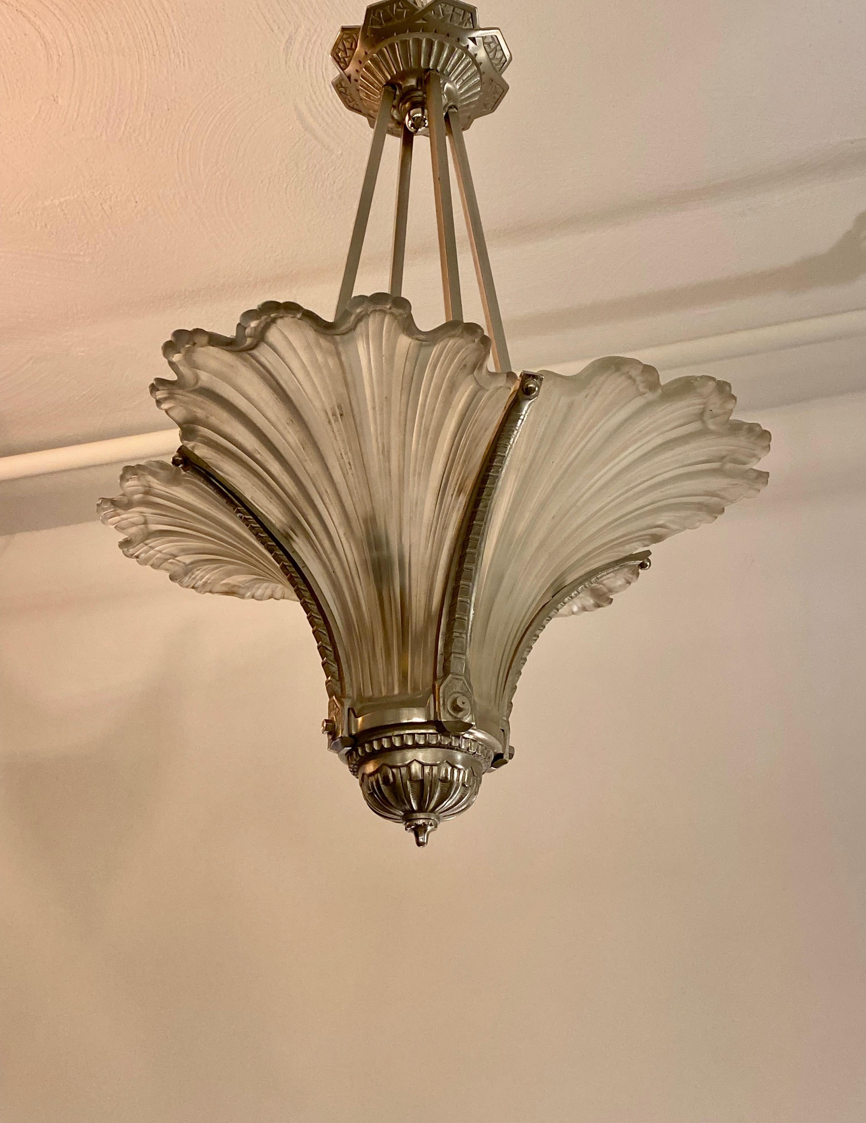 French Art Deco pendant chandelier having four ribbed glass panels. Resting in a nickel geometric design frame. Having beautiful Deco details throughout. Has been rewired for American use with four candelabra sockets. Each socket has a max watt of