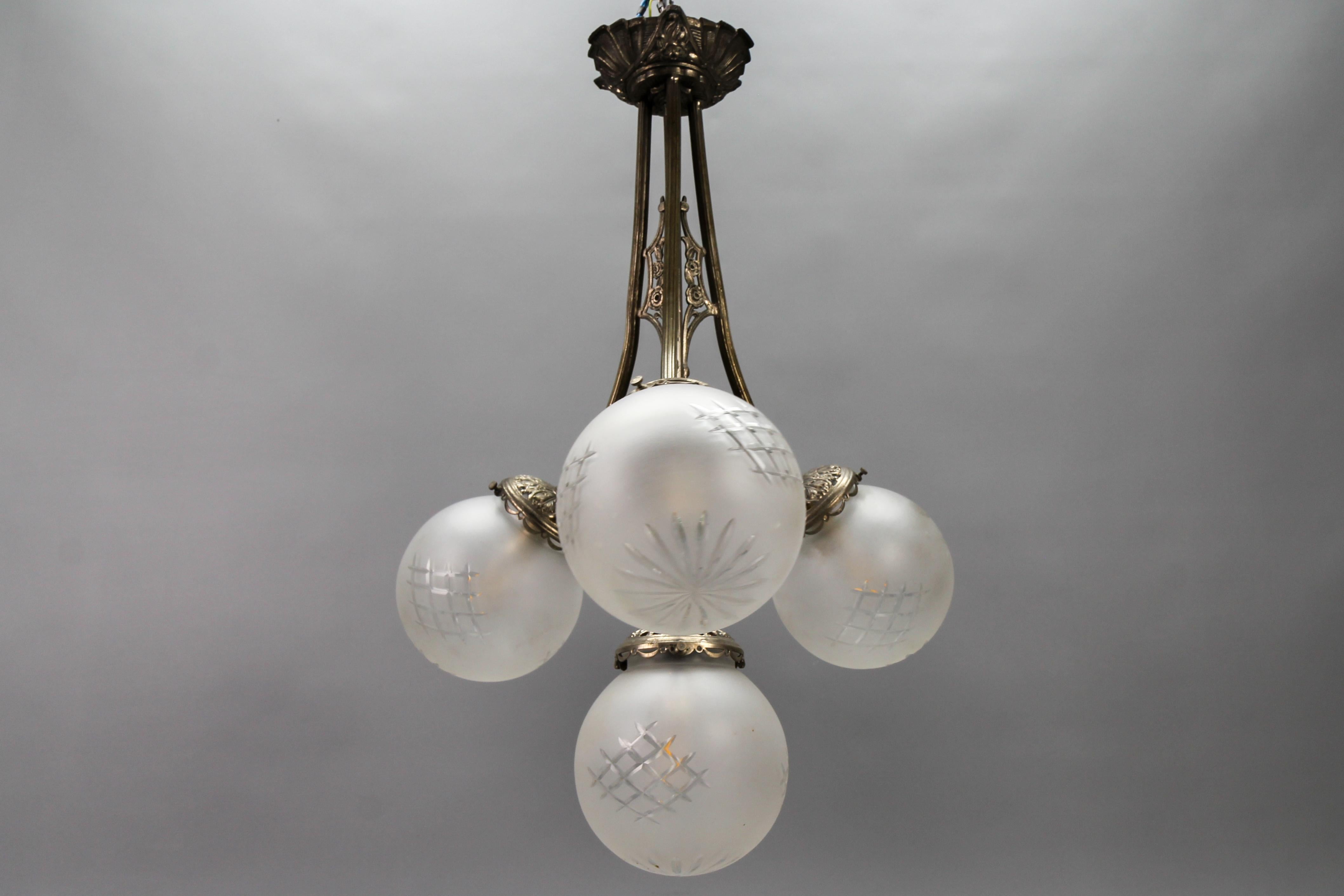 Milieu du XXe siècle Lustre suspendu Art déco français à quatre lumières en laiton et globes en verre taillé dépoli en vente