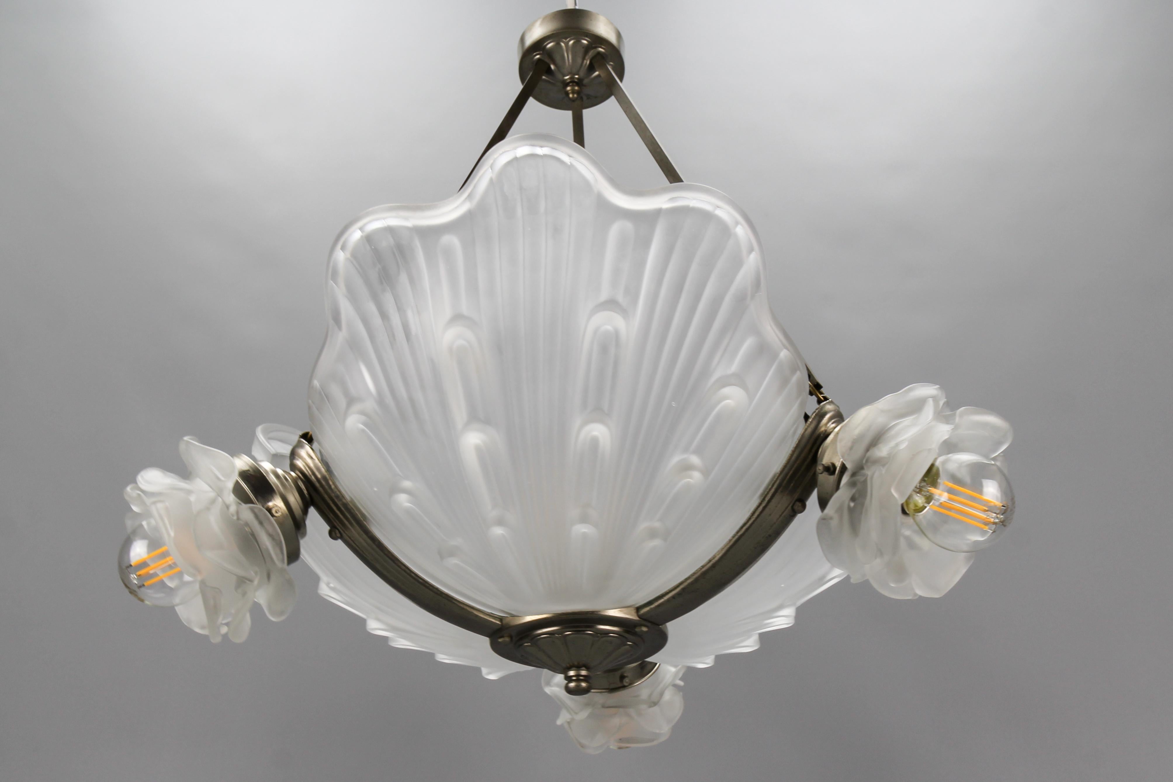 Vierflammiger Muschelkronleuchter aus weißem Milchglas, Art Deco, Frankreich, ca. 1930er Jahre.
Dieser schöne französische Art-Déco-Kronleuchter hat einen Rahmen aus vernickeltem Messing mit drei muschelförmigen Lampenschirmen aus weißem Milchglas
