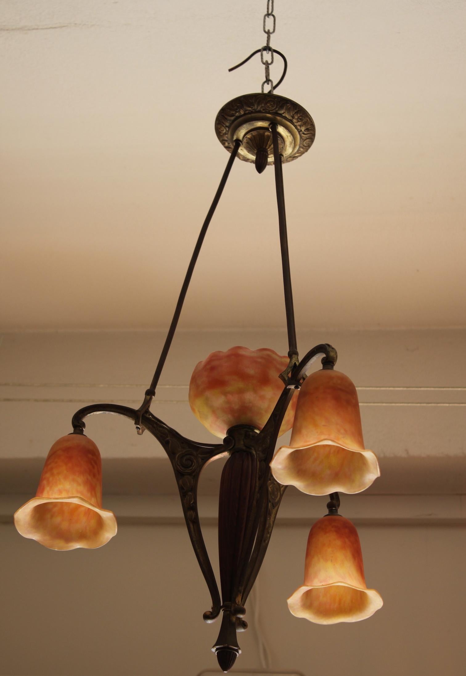 Art Deco Daum four-light chandelier with wooden and patinated bronze structure, can be Majorelle or Brandt. Four jade glass bulb covers, including three polylobed tulips and a central corolla in form of a flower, pink-orange and yellow colored