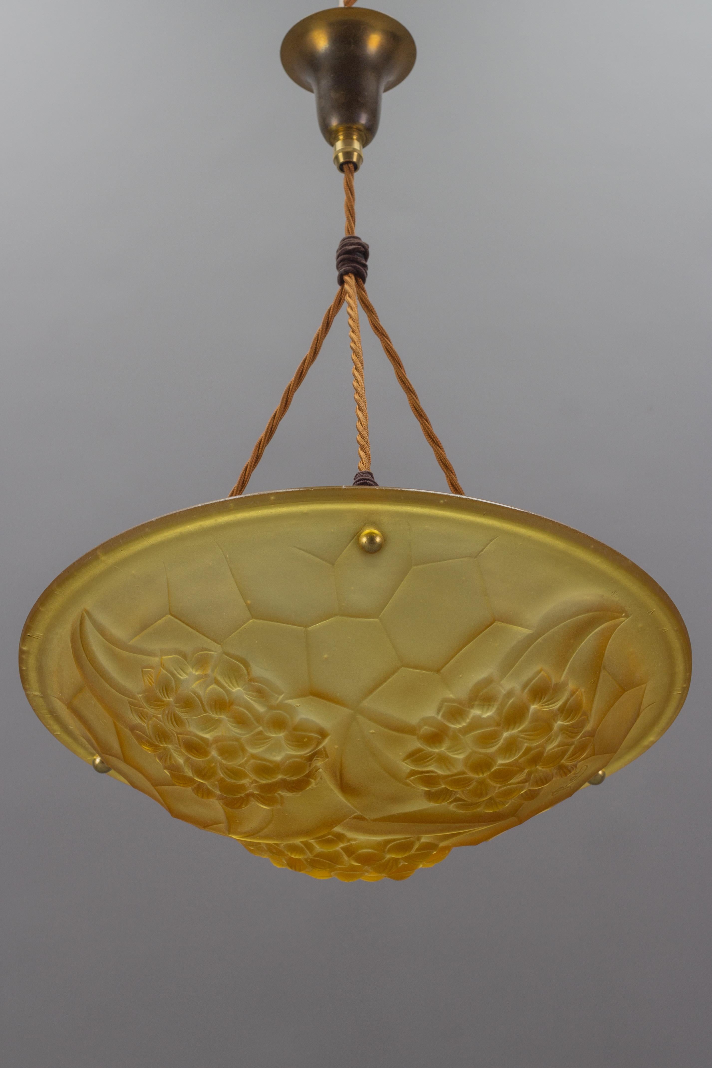 Beautiful French Art Deco period frosted molded glass shade in amber color with a floral and geometric design, signed ROS, by David Gueron for Cristalleries de Compiègne. Numbered with 706.
Suspended by three ropes with a brass canopy on the