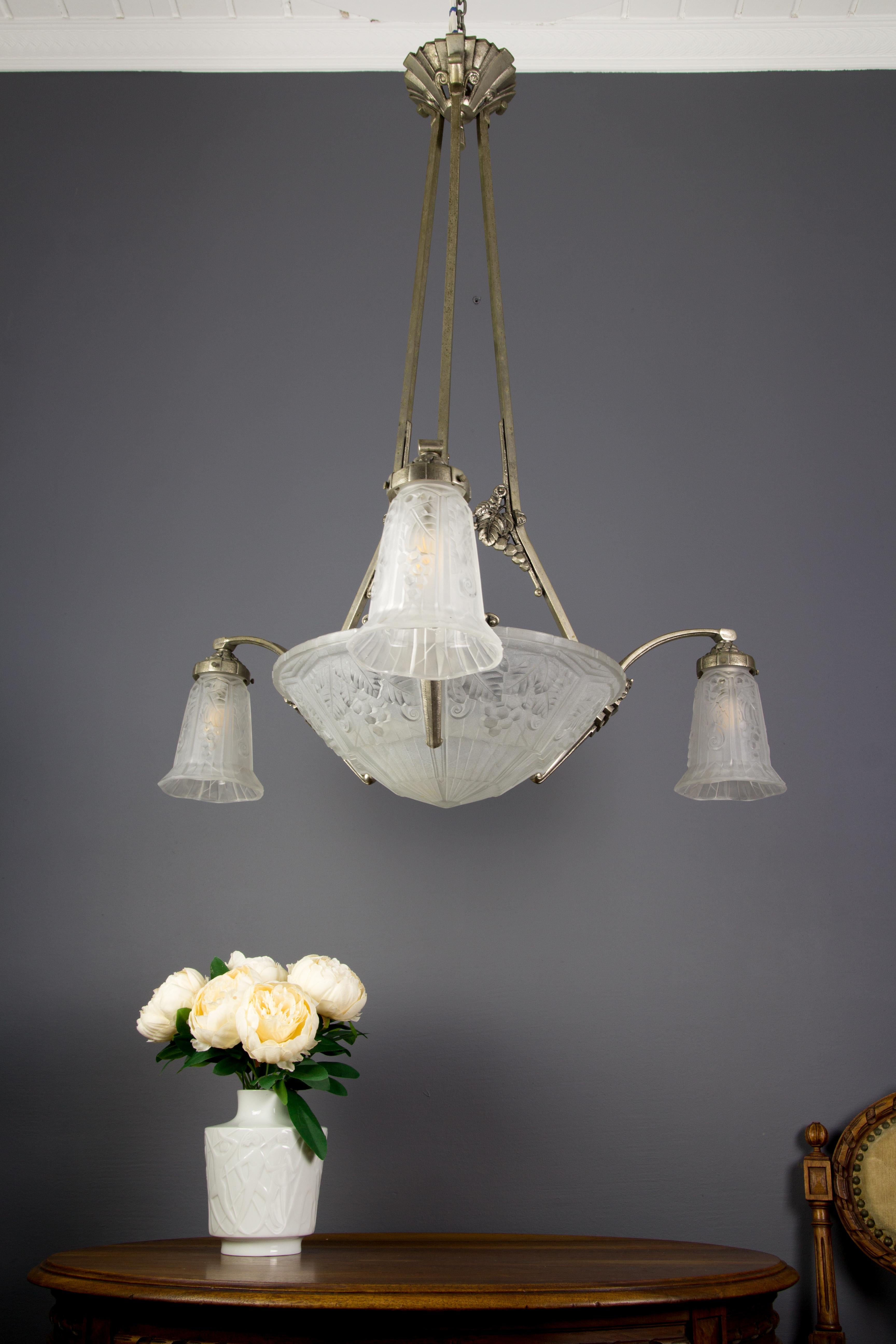 Beautiful Art Deco chandelier, made in France and signed by Pierre Maynadier. The frame of this lamp is made of nickel-plated silvered bronze. The lampshades are made of frosted glass. The central glass bowl and three tulip glass shades bear the