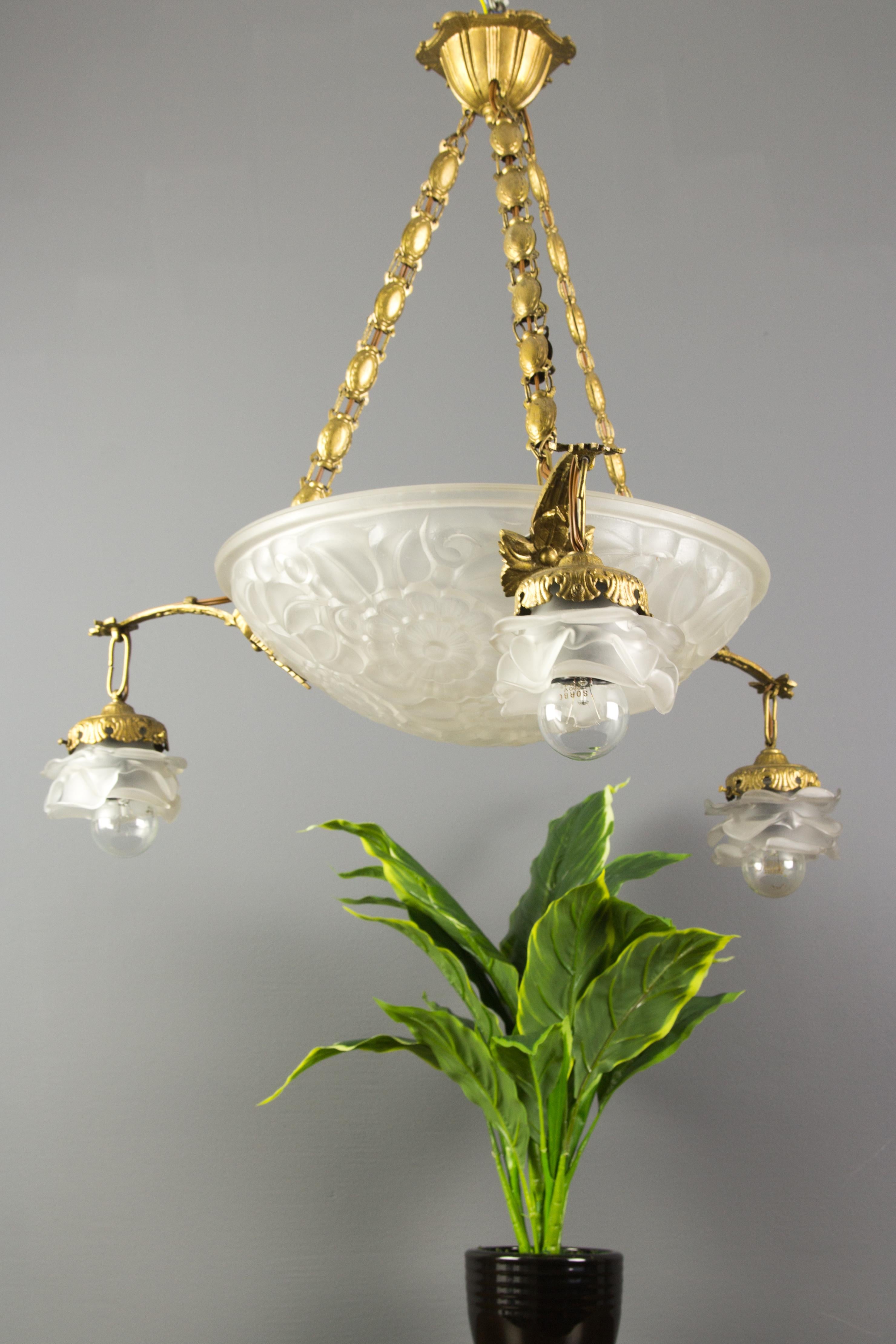 A beautiful French 1930s Art Deco chandelier with a central molded-pressed glass bowl, ornate with floral and deco motif and signed Primaflore, France. It is unknown which glass factory made this glass bowl, possibly Schneider or Degué. The three