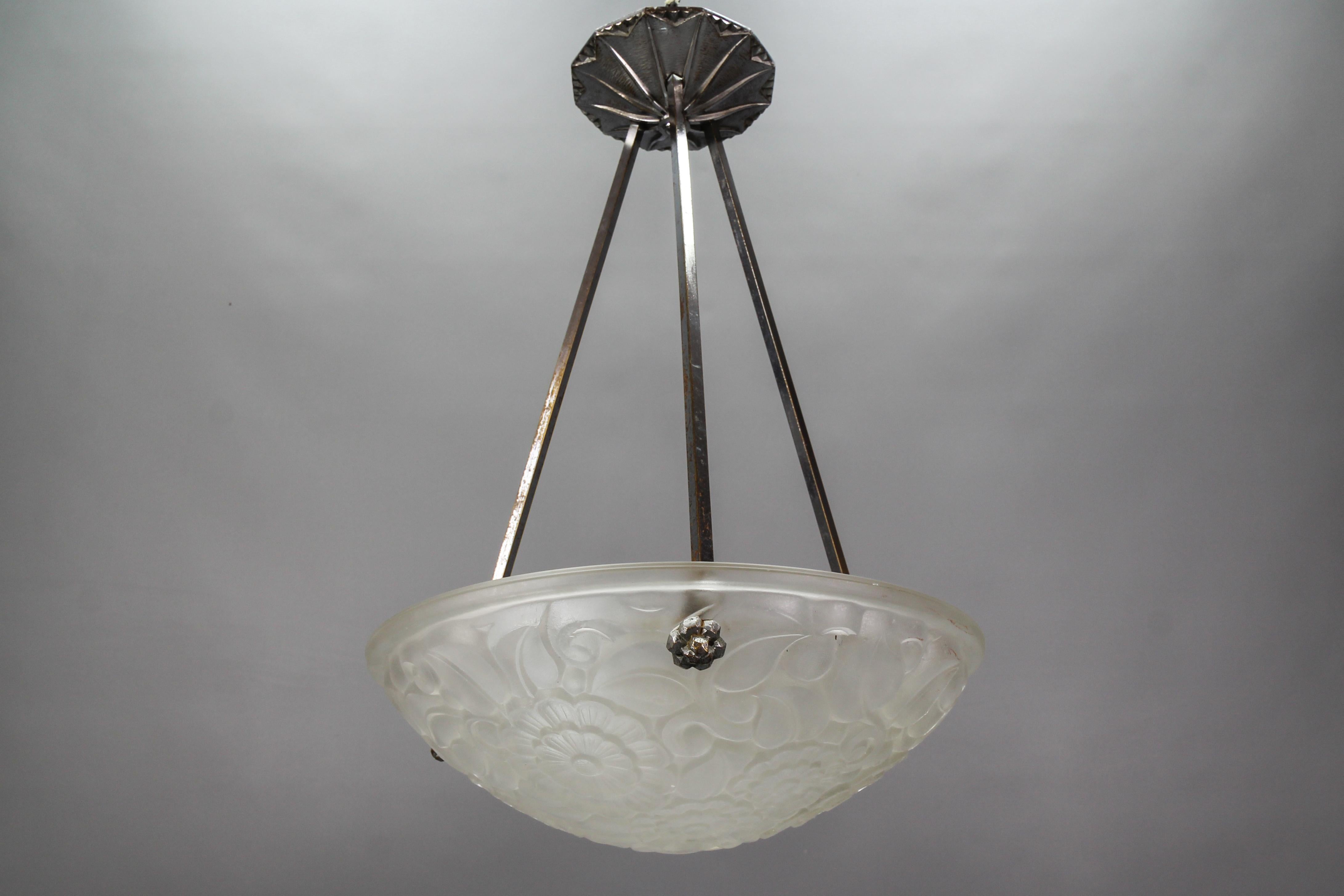 French Art Deco pendant light with a frosted clear glass lamp shade/bowl from the 1930s.
This beautiful clear frosted glass bowl features stylized flower motifs, marked on the edge 