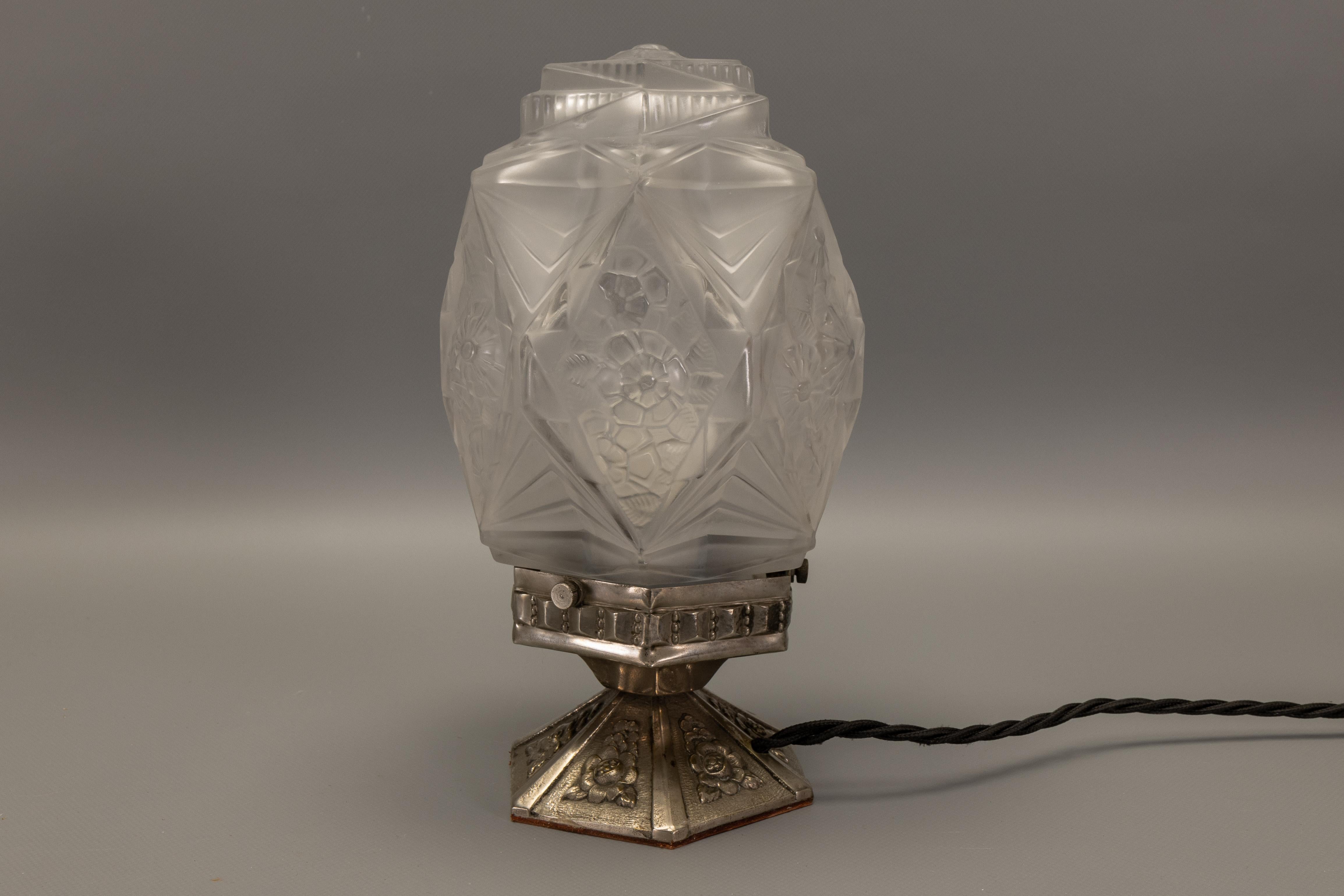Encantadora lámpara de mesa francesa Art Decó de los años 30, con cristal esmerilado geométrico, complementada con una base decorativa de latón niquelado. Un acento ideal para coleccionistas e interiores que buscan una auténtica elegancia de