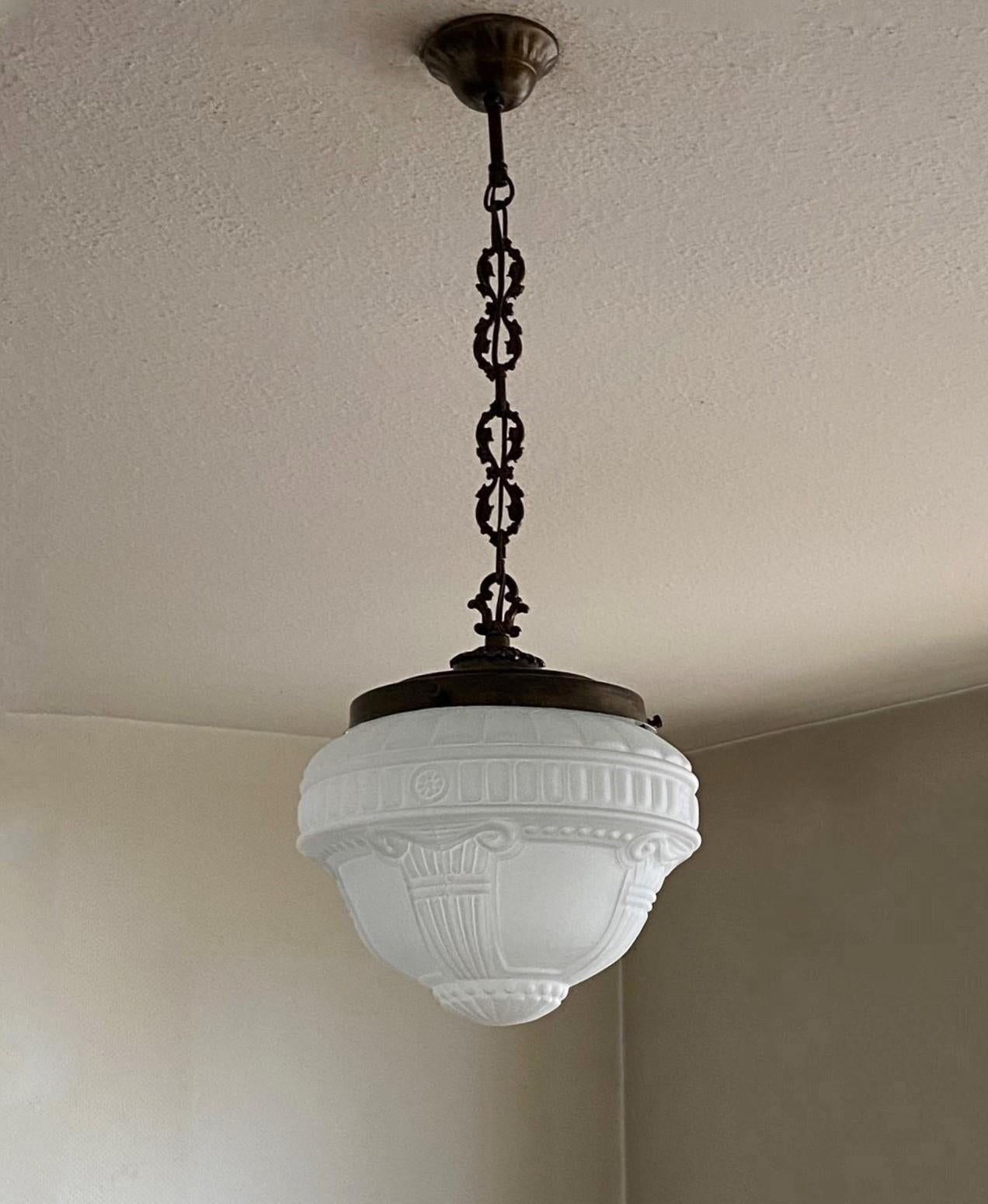 An elegant Art Deco  high relief glass pendant, light fixture, France 1920-1929, frosted glass globe with beautiful detailing, patinated brass mounts. In Fine vintage condition, glass without damages, newly rewired. It takes 1 Edison E27 screw bulb