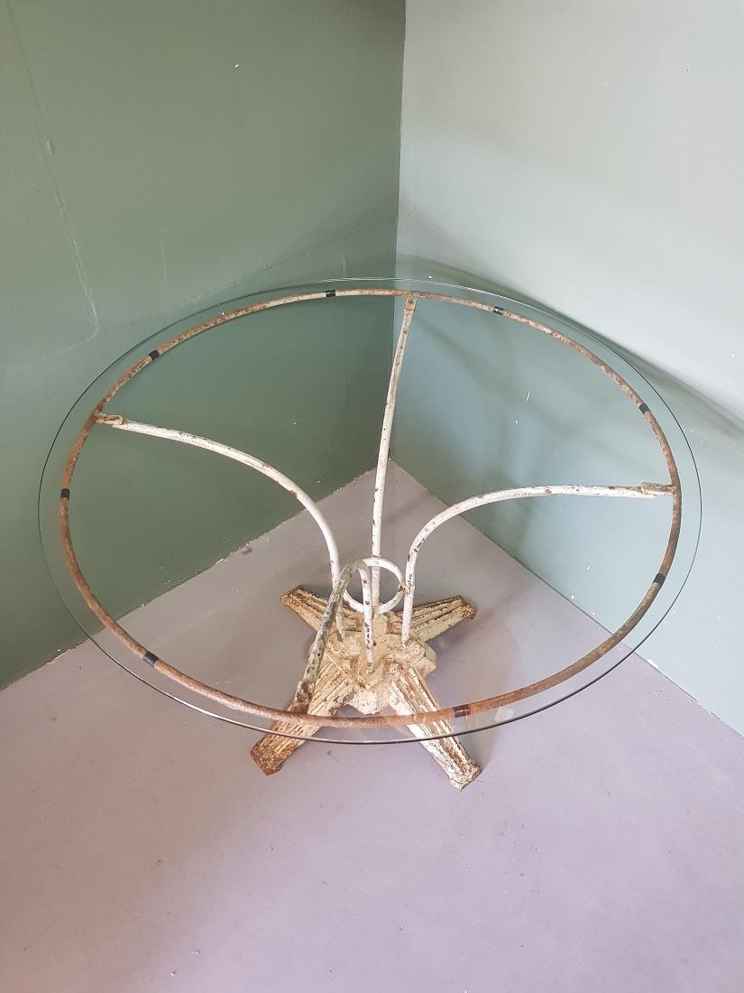 French Art Deco garden table with glass top and metal frame that has a weathered appearance, is further in a good but used condition. Originating from the 1st half of the 20th century.

The measurements are:
Diameter 103 cm/ 40.5 inch.
Height