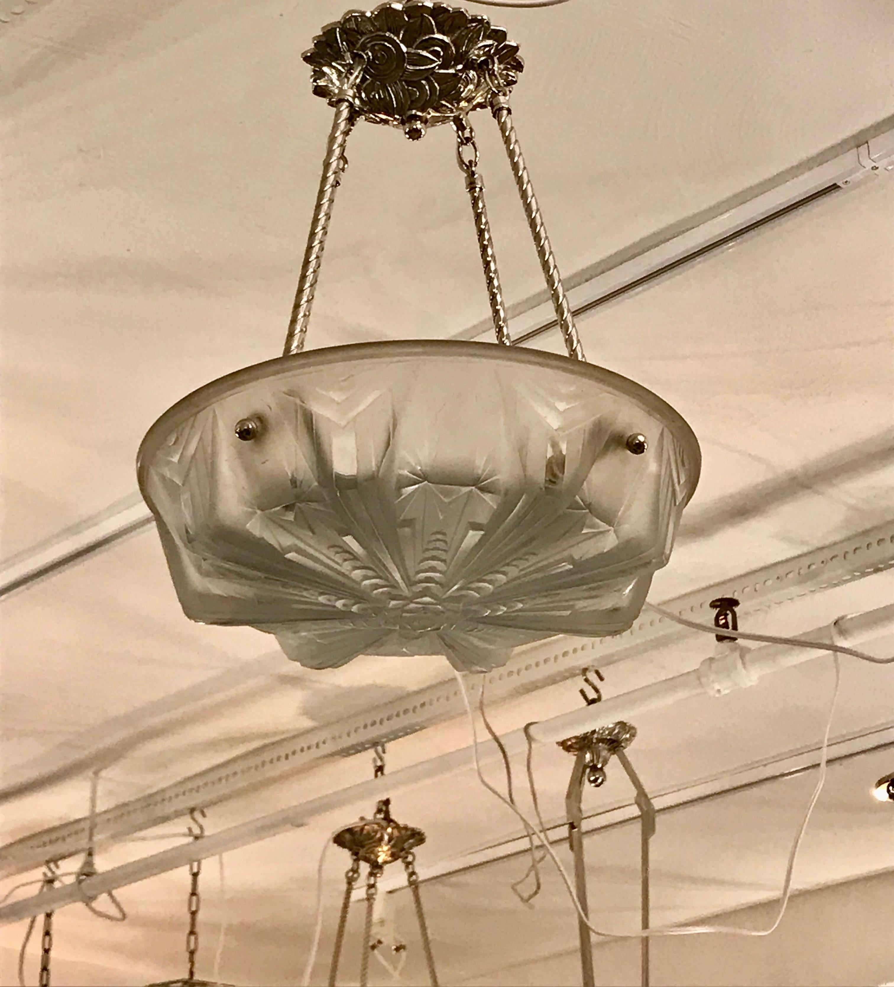 French Art Deco chandelier by Muller Frères Luneville. With beautiful clear frosted glass bowl with geometric motif. Held by four nickel-plated metal rods and floral ceiling plate. Has been rewired for American use. Four candelabra sockets each with