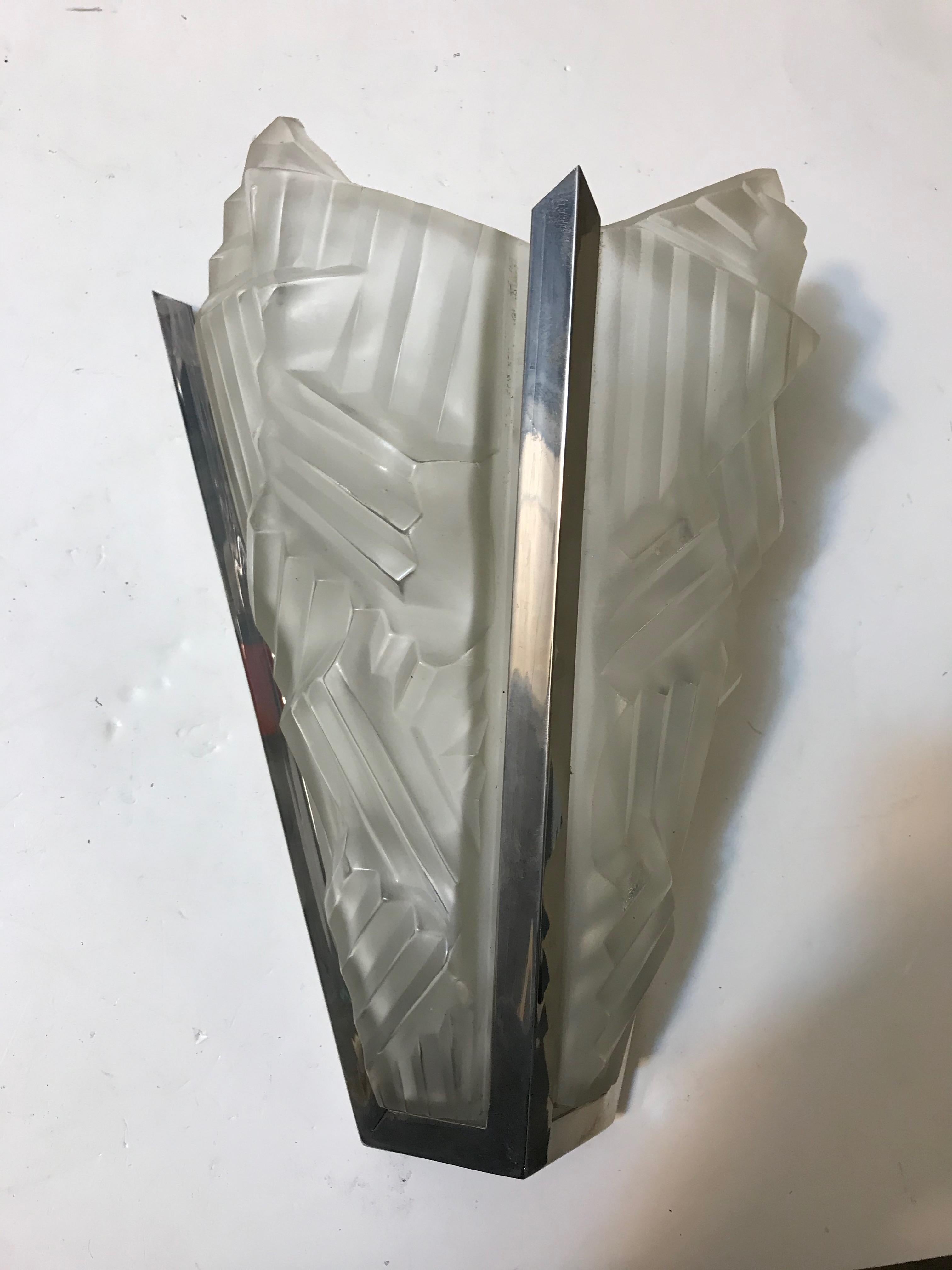 Single French Art Deco sconce signed by Degué. Having two clear frosted glass shades with geometric motif details throughout. Held by nickel design frame. Has been rewired for American use. The sconce takes one 60 watt candelabra bulb. Re plating