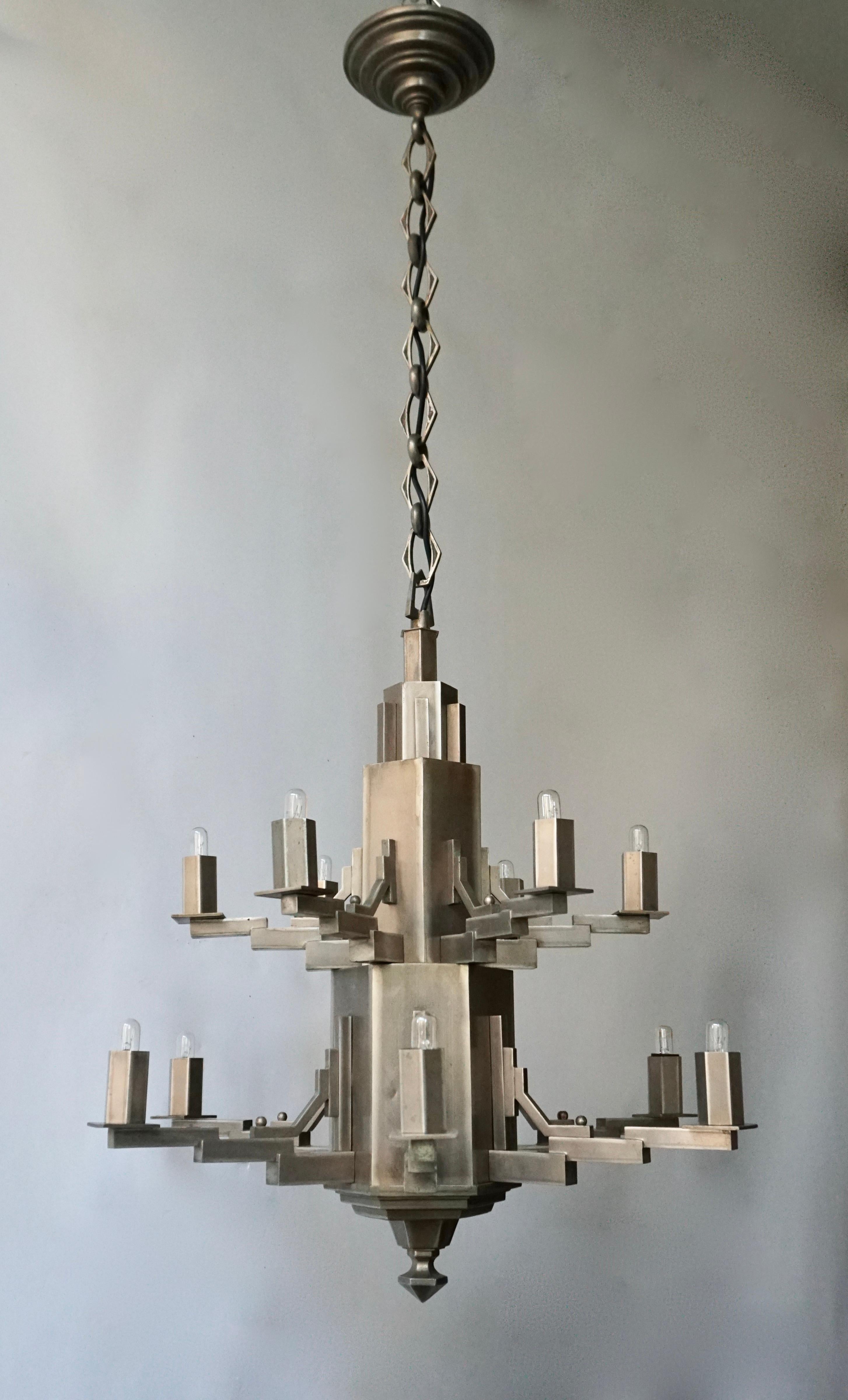 French Art Deco twelve-light chandelier with a two-tiered geometric base.

The light requires twelve single E14 screw fit lightbulbs (60Watt max.) LED compatible.

Measures: Diameter 56 cm.
Height fixture 65 cm.
Total height including chain