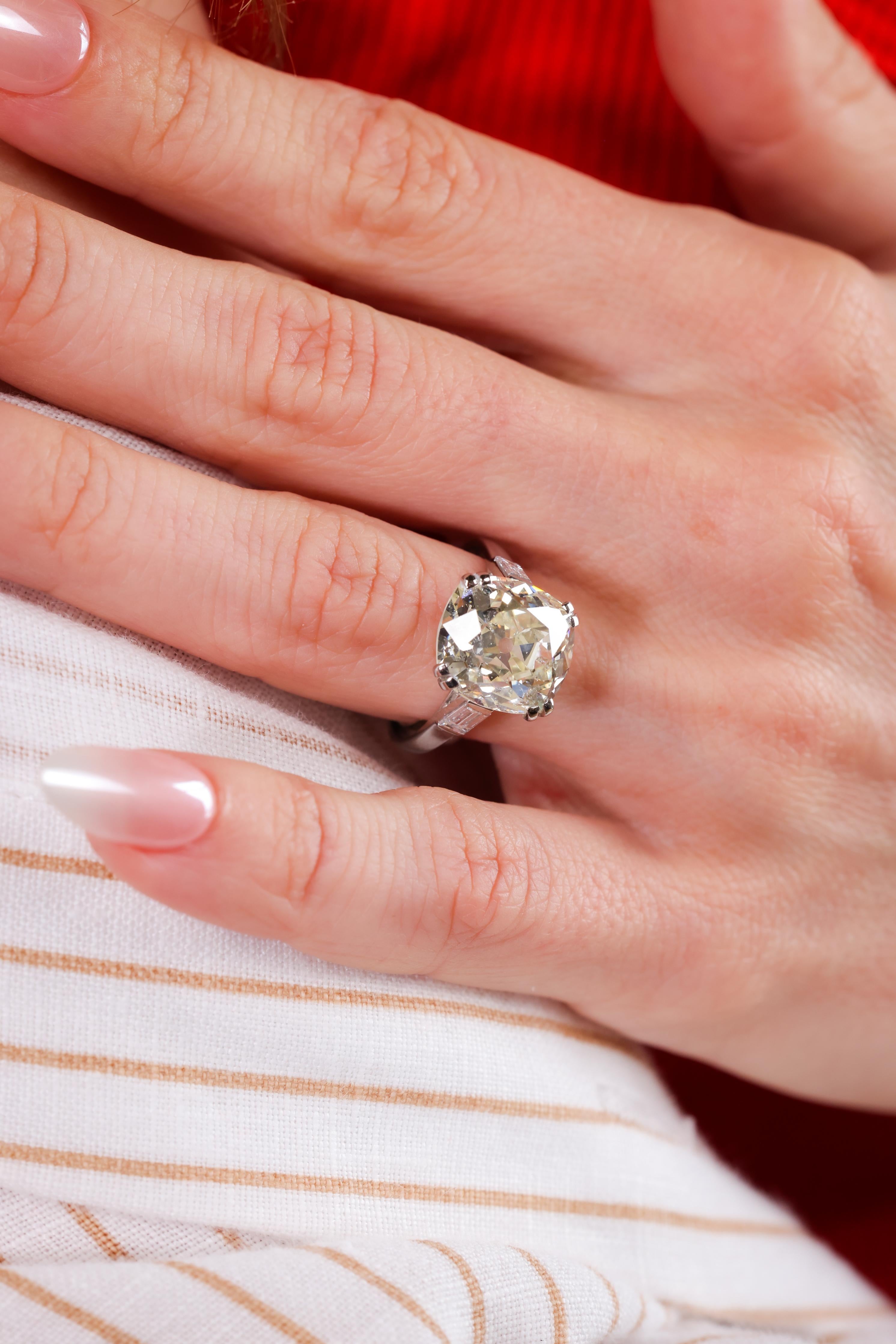 Certificate: GIA
Center Stone: Diamond
Cut: Old Mine
Weight: 7.60
Color: O-P
Clarity: I1 
Accent Stone: 2 diamonds 
Cut: Tapered Baguette 
Weight: 0.30 carats approximately 
Color: F-G
Clarity: VS
Metal: Platinum 
Era: Art Deco
Circa:
