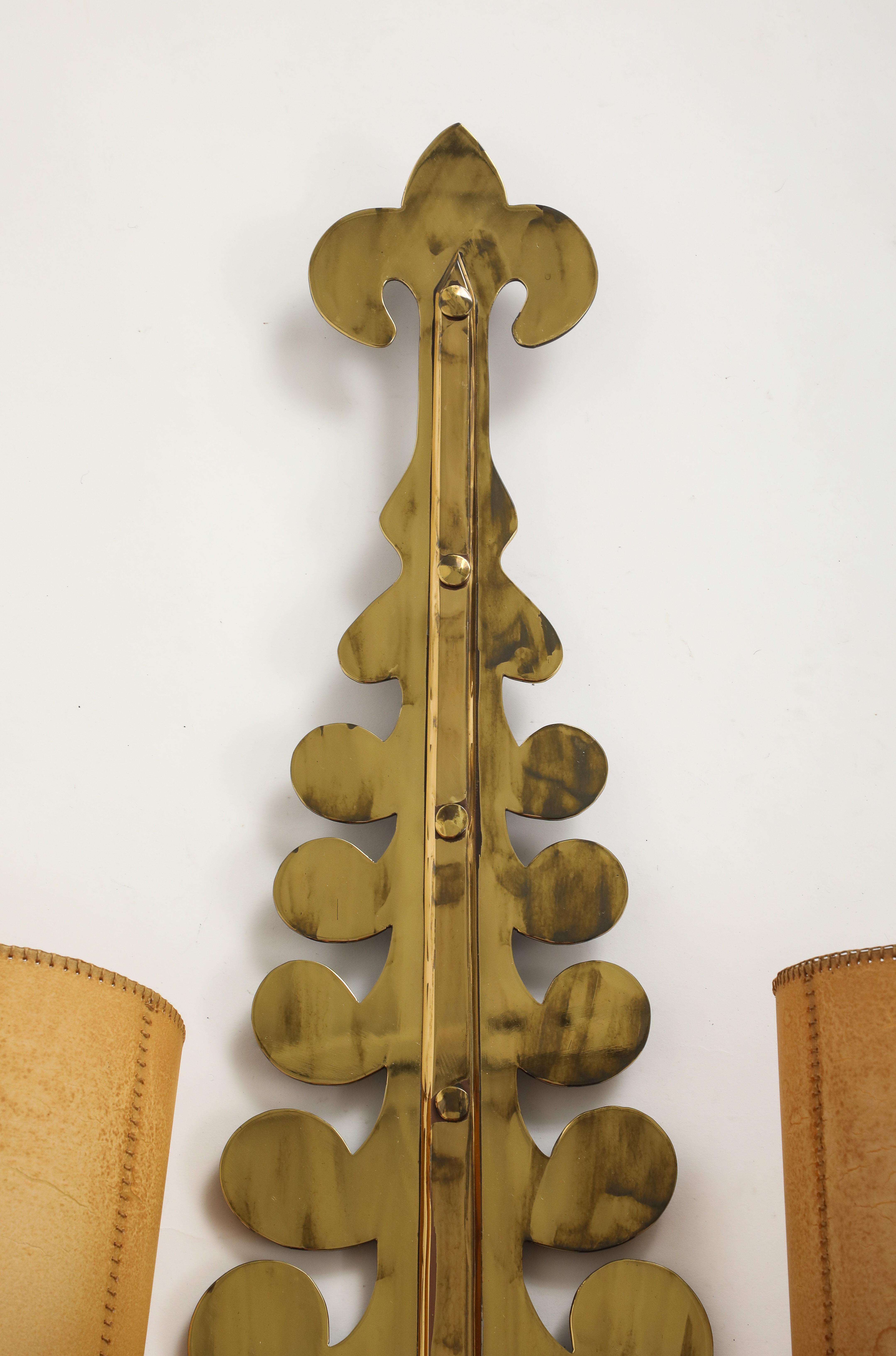 Une élégante applique murale en forme de volute en laiton doré, fabriquée en France vers 1940. Trois (3) prises avec abat-jour en parchemin ajoutent de la chaleur et de l'ambiance. L'artisanat reflète l'influence Art déco de l'époque, caractérisée