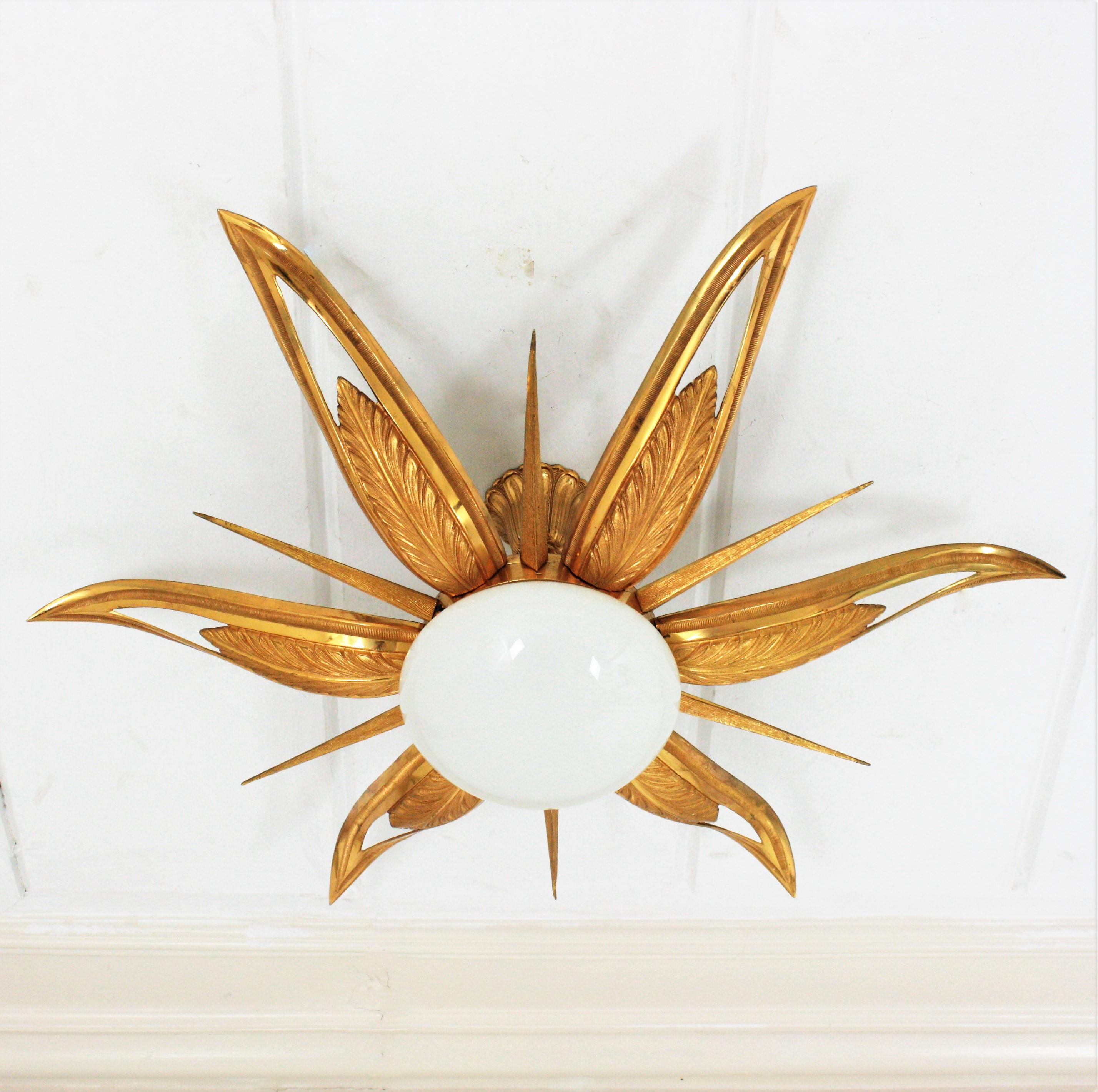 An exceptional Art Deco starburst shaped engraved and molded bronze ceiling lamp, France, 1930s-1940s.
This flush mount features a flower burst or starburst with 6 large leaves or rays, 6 pointed smaller and thinner rays and an opaline white glass