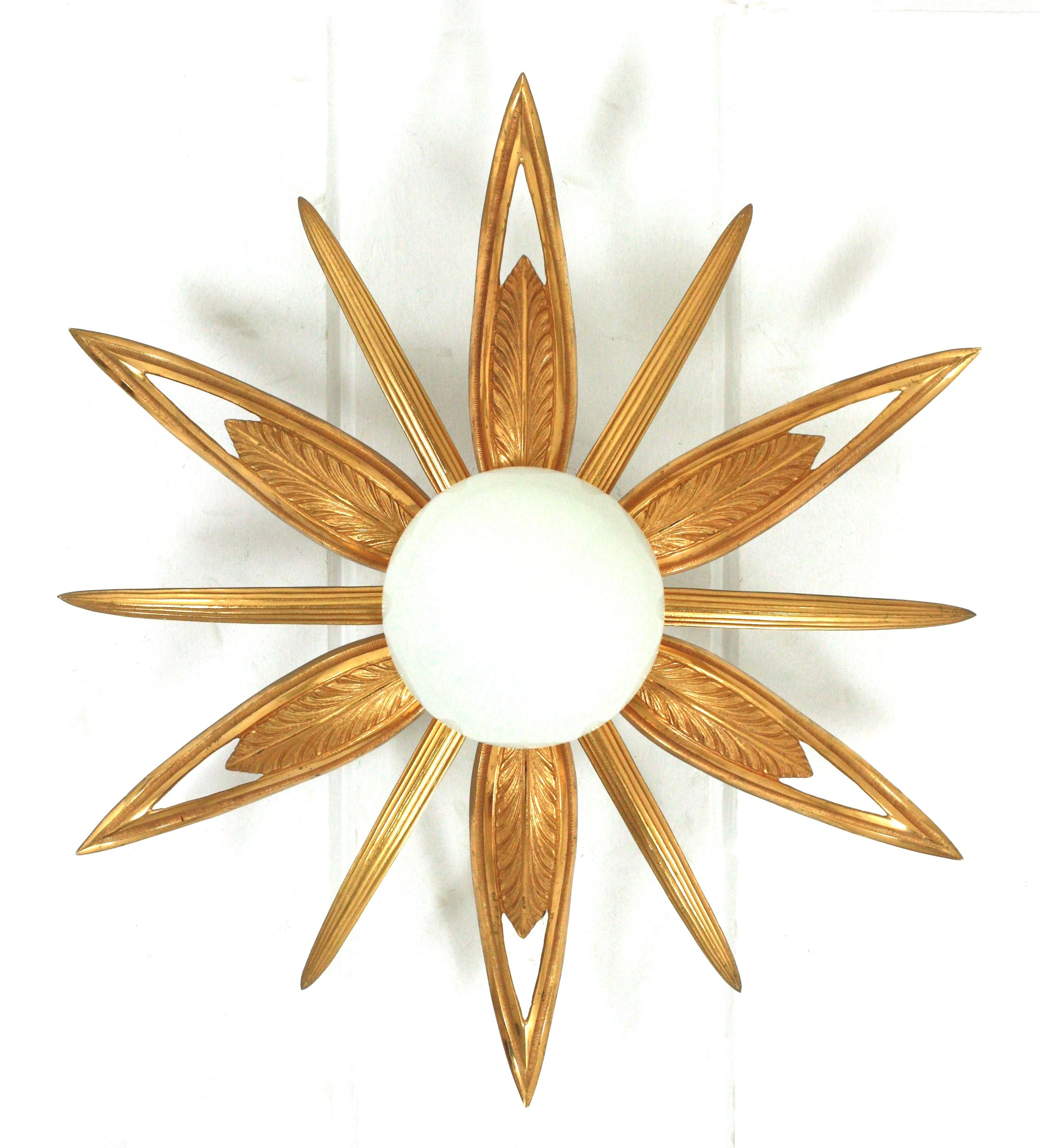 An exceptional Art Deco starburst shaped engraved and molded bronze ceiling lamp, France, 1930s-1940s.
7 lights
This flush mount features a flower burst or starburst with 6 large leaves or rays, 6 pointed smaller rays and an opaline white glass