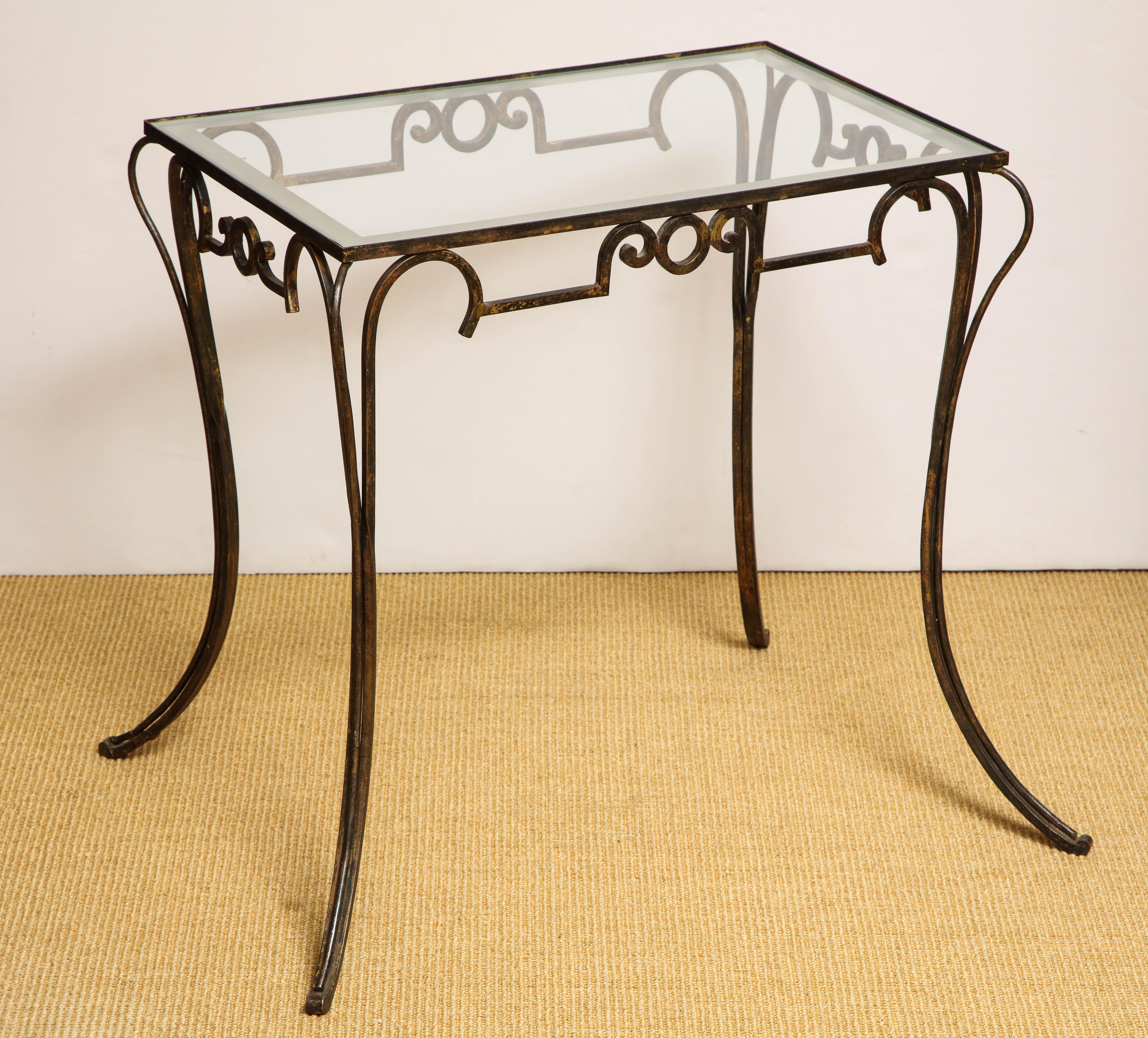 The glass inserted top supported by a scroll work iron base with partial gilding.