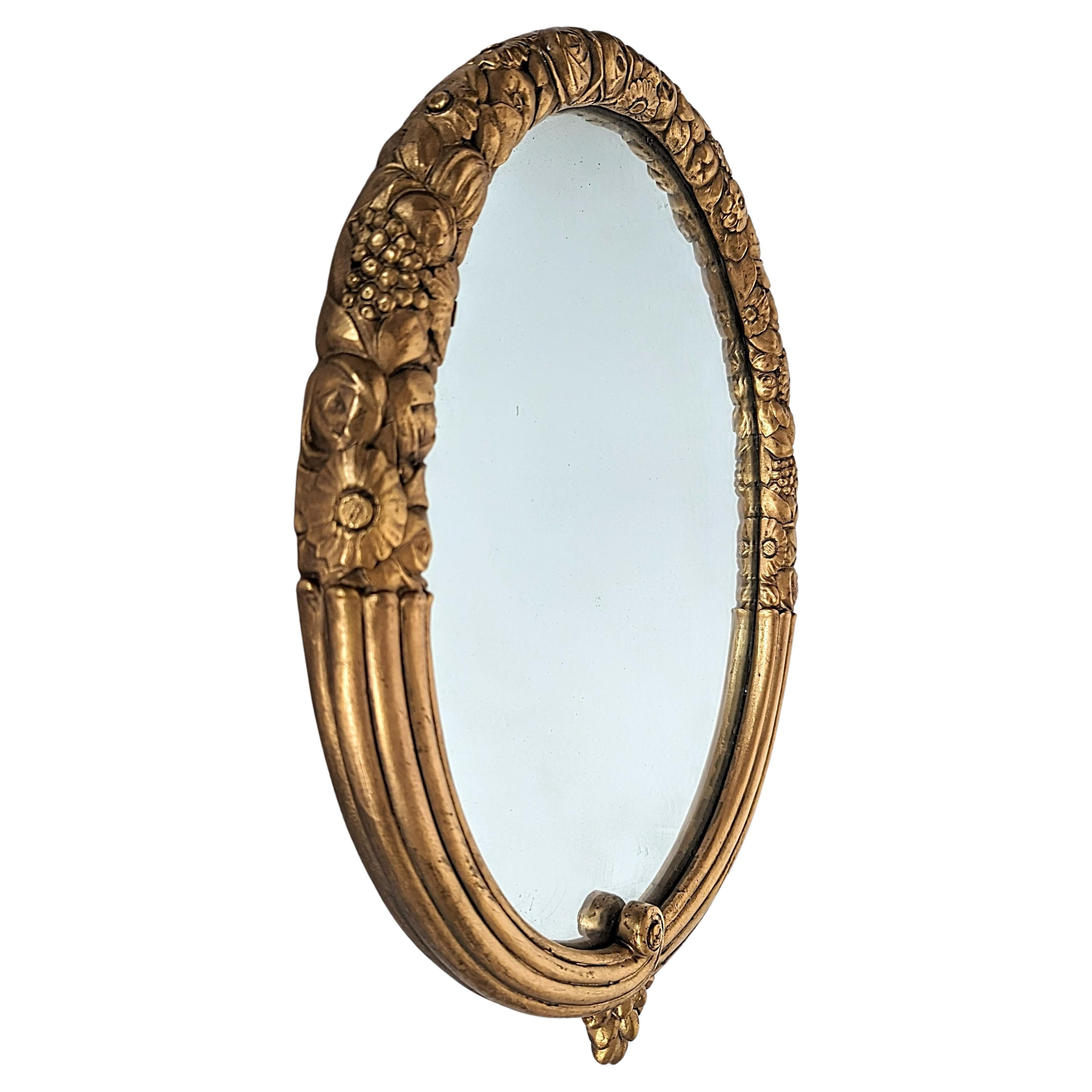 By LOUIS SUE AND ANDRE MARE. 
This rare Art Deco oval mirror made by Sue and Mare (Louis Sue, 1875-1968, and Andre Mare, 1887-1932) has a frame of hand-carved gilt wood. The upper section has a floral carving with Golden gilding that extends with