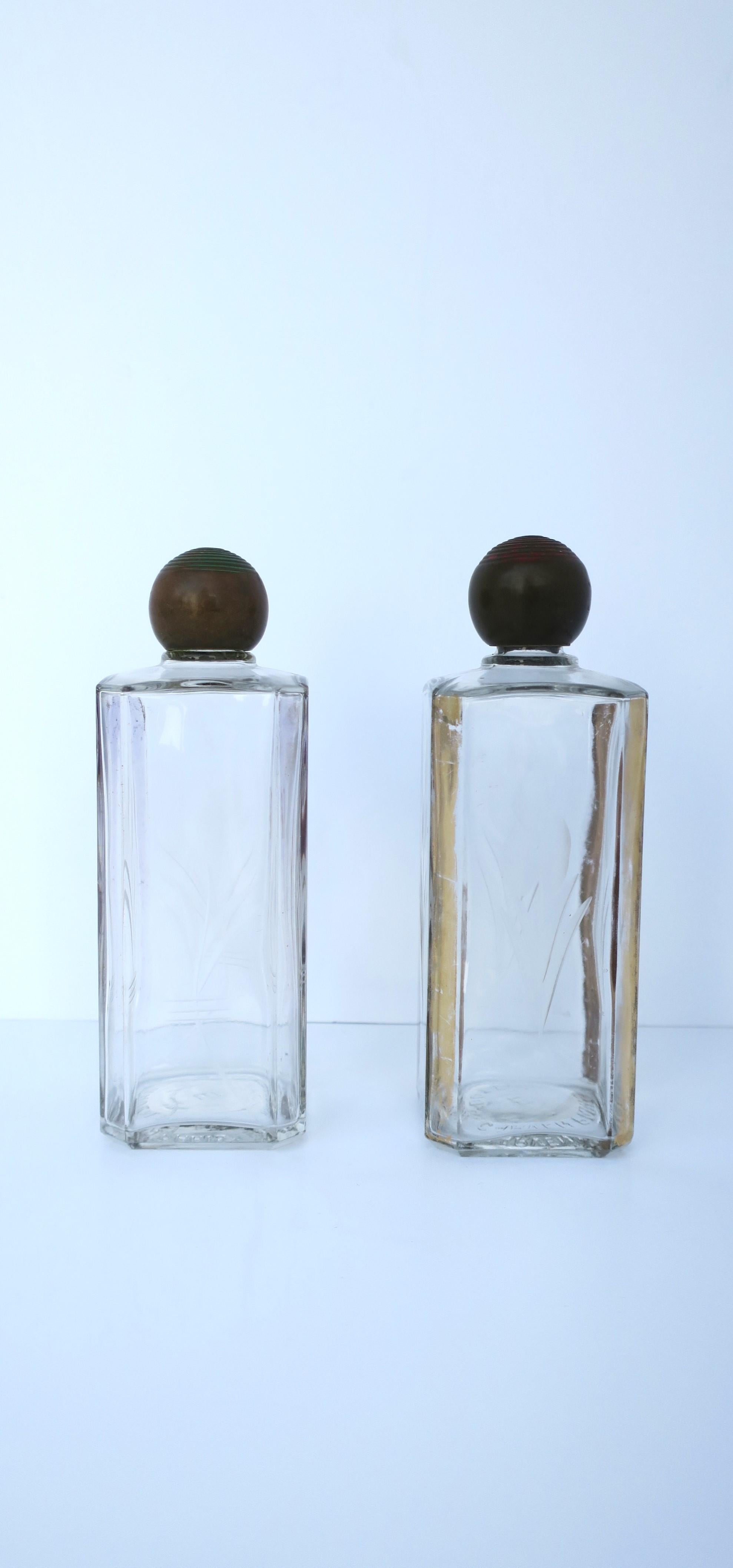 A beautiful pair of French Art Deco period perfume glass bottles with etched design, gold gilt accent, and bronze tops, from luxury fashion Maison Carven, circa early-20th century, 1940s, Paris, France. Bottles have a modern floral etched design on