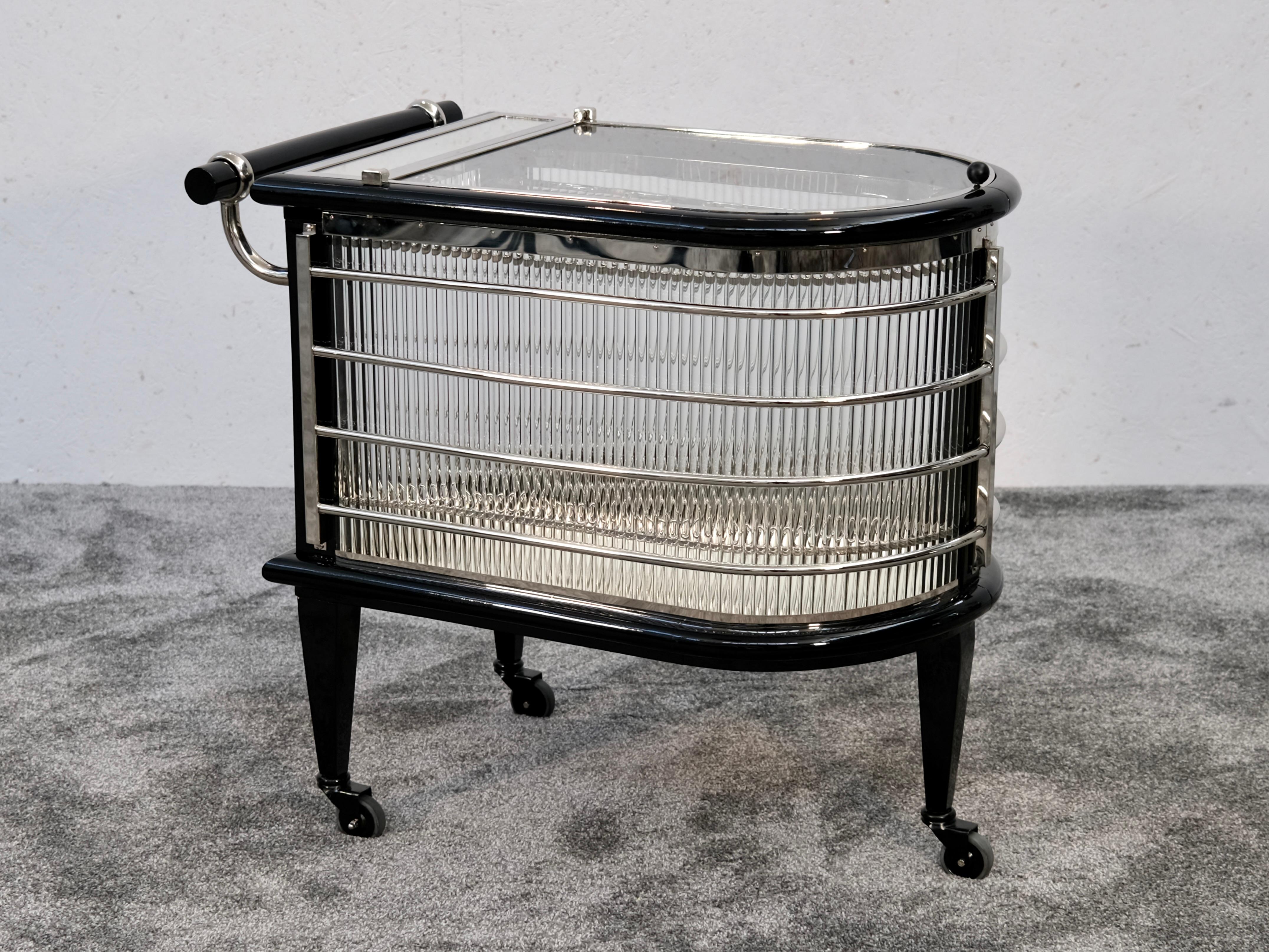 Este excepcional carrito de bar Art Déco francés de los años 30 cautiva por su estructura arquitectónica y su refinada interacción de materiales. Apoyada sobre tres patas cónicas con ruedas, la pieza irradia dinamismo y equilibrio gracias a su
