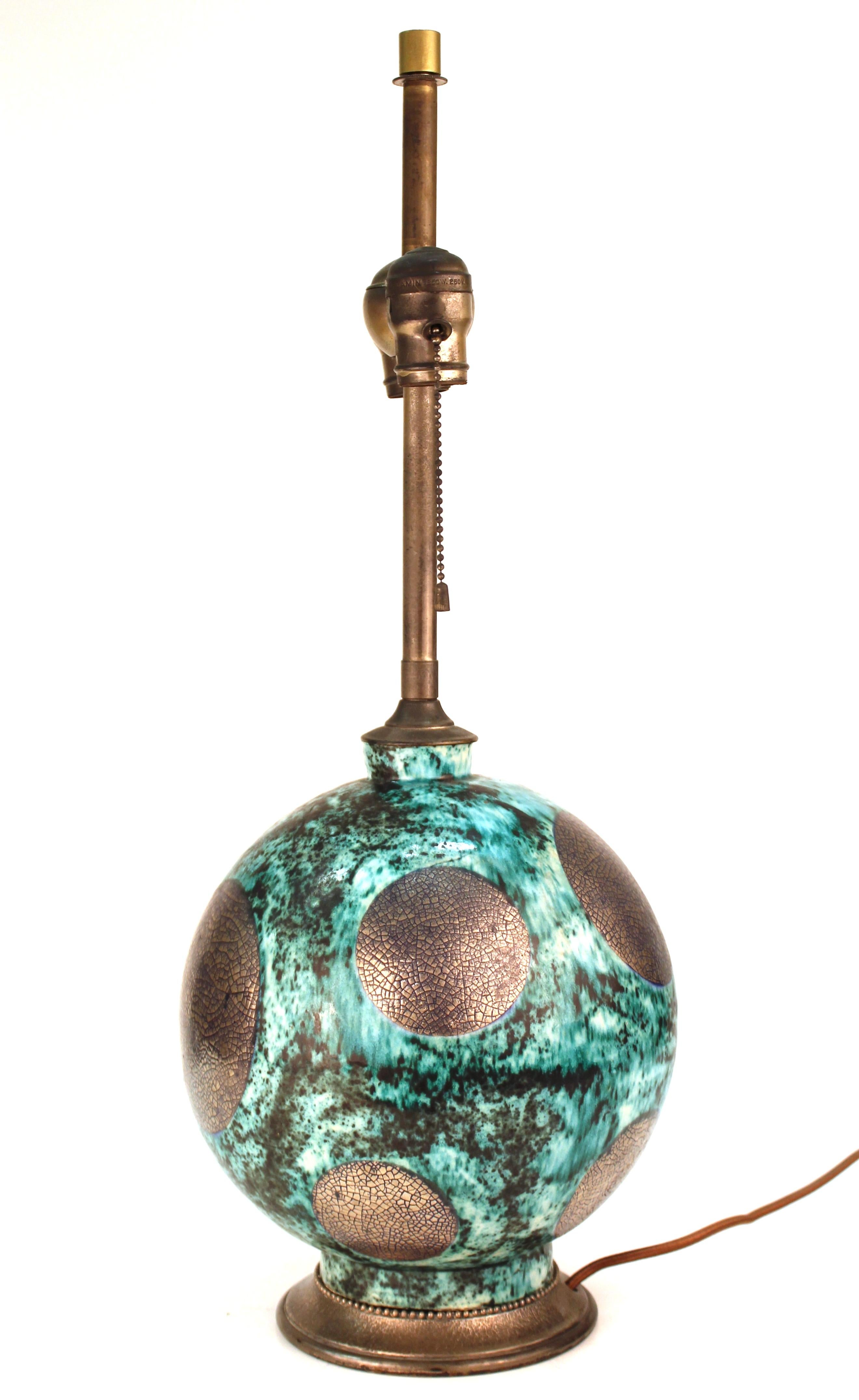 Lampe de table d'époque Art Déco avec corps sphérique en céramique émaillée et partiellement argentée et petit vase assorti. La lampe de table a une monture en bronze argenté. Le petit vase présente le même motif de sphère et est signé sur le fond