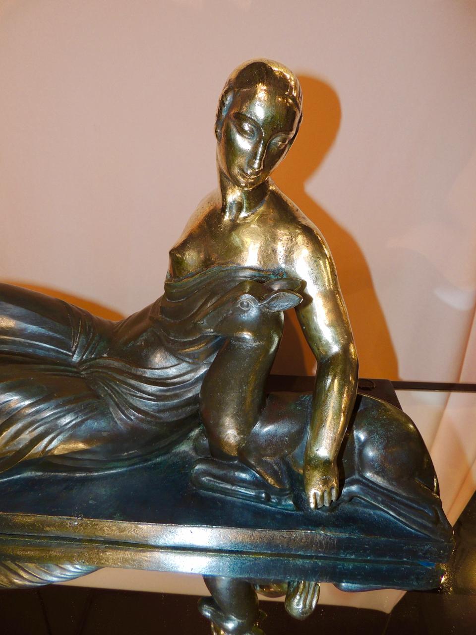 A French bronze sculpture in the pastoral and Classic Art Deco image of a woman and deer. Partially nude, but draped in elaborate folds of dark bronze which contrasts the brilliant gold tones of her skin and tresses. The artist is Gaston Beguin,