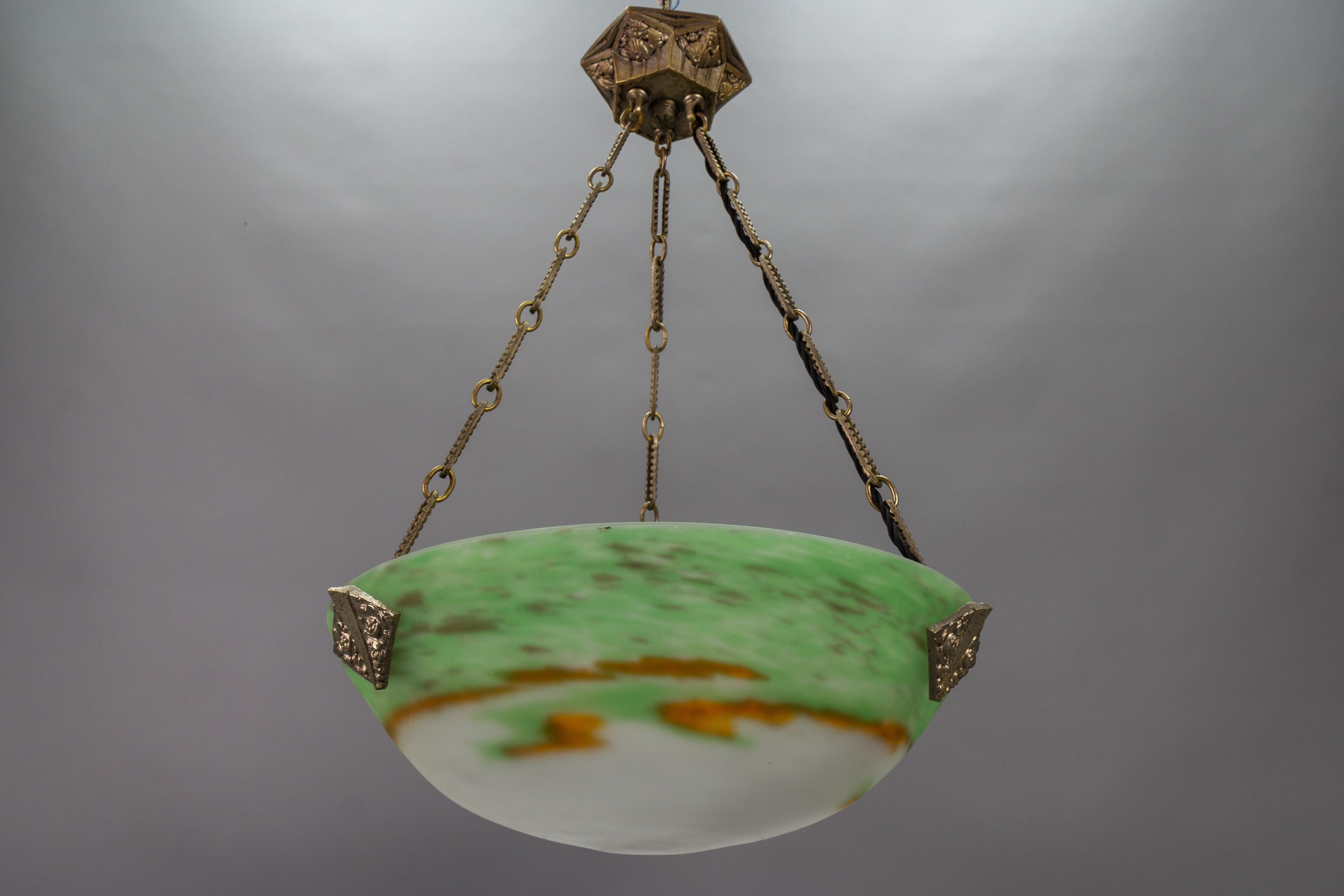 French Art Deco bronze and Pâte de Verre glass pendant light fixture by Muller Frères Luneville from circa the 1920s.
This delightful French Art Deco period pendant light features a green and white color 'Pâte de Verre' glass bowl with orange tones.