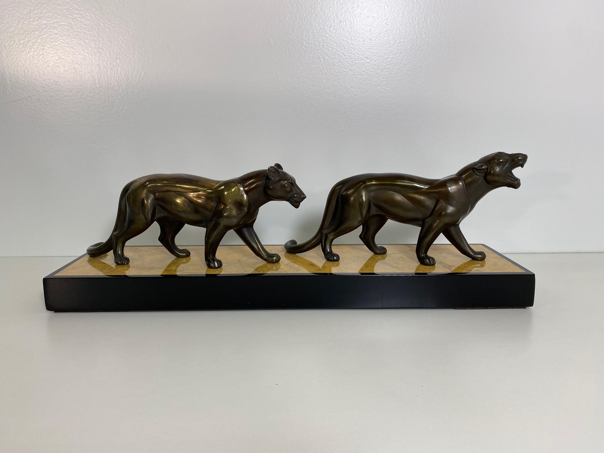 This Art Deco group of panthers sculpture was produced in France in the 1930s. 
The panthers are in metal with a bronze patinated effect, while the base is in Siena yellow marble.