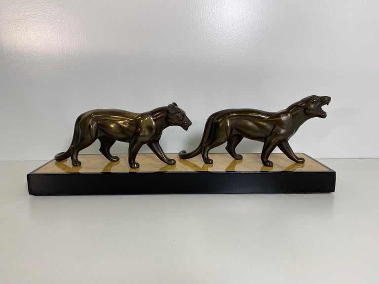 This Art Deco group of panthers sculpture was produced in France in the 1930s. 
The panthers are in metal with a bronze patinated effect, while the base is in Siena yellow marble.