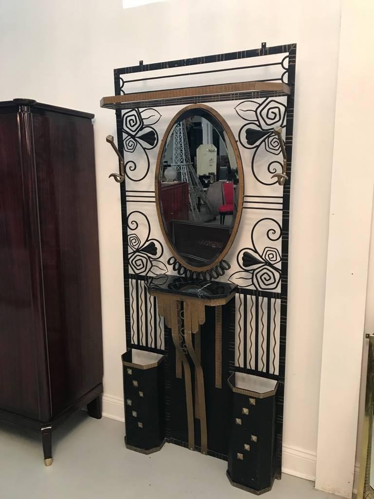 French Art Deco Edgar Brandt style hall tree with two umbrella stands. Having gilt and black ironwork accents. Beautiful marble shelf below a central oval beveled mirror. Two coat hangers and upper shelf for hats. The hall tree has geometric and