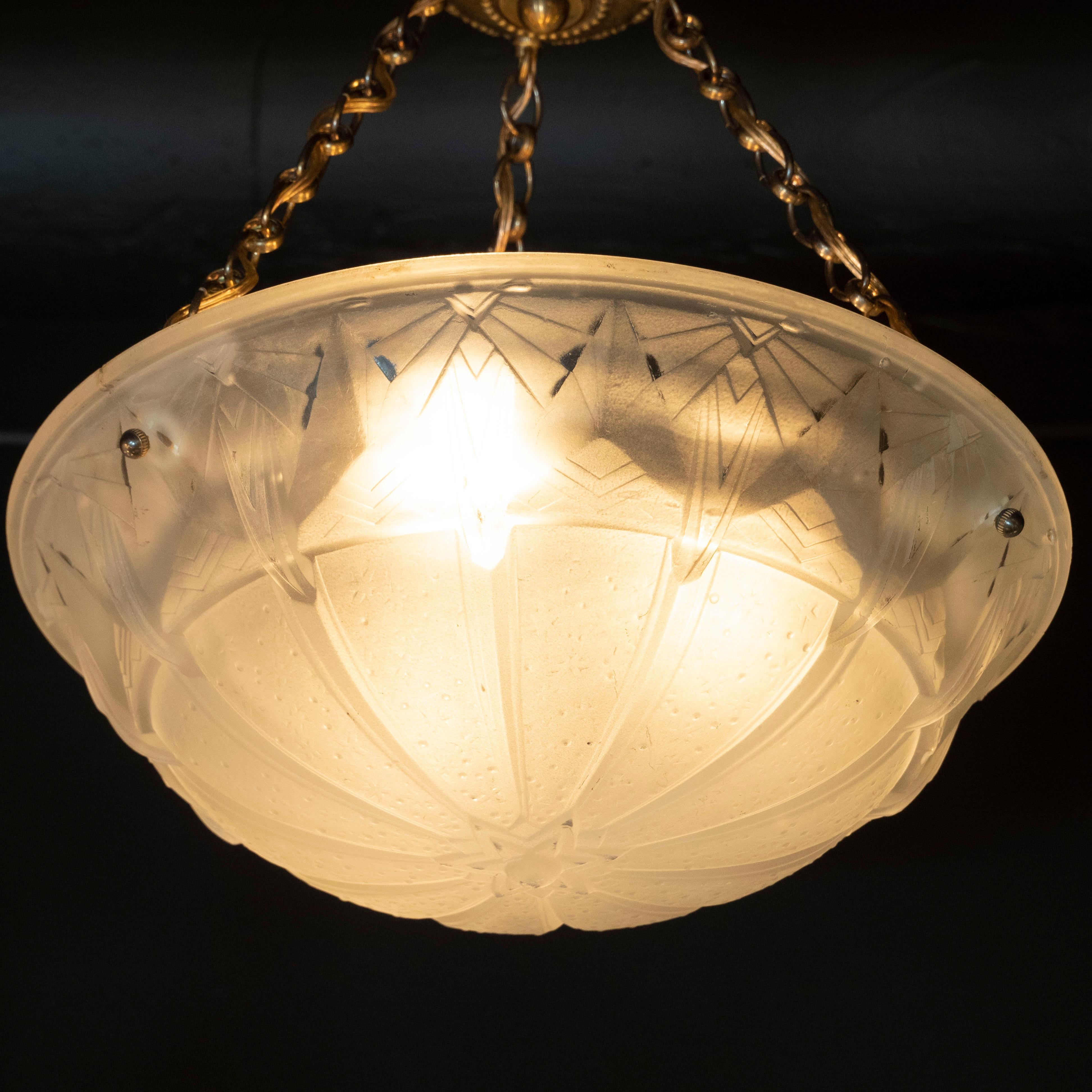 This elegant Art Deco pendant was handblown in the studios of Muller Frerès in France, circa 1935. It features a convex domed circular body with intricate and iconically Art Deco geometric designs inscribed throughout. The glass shade affixes to the