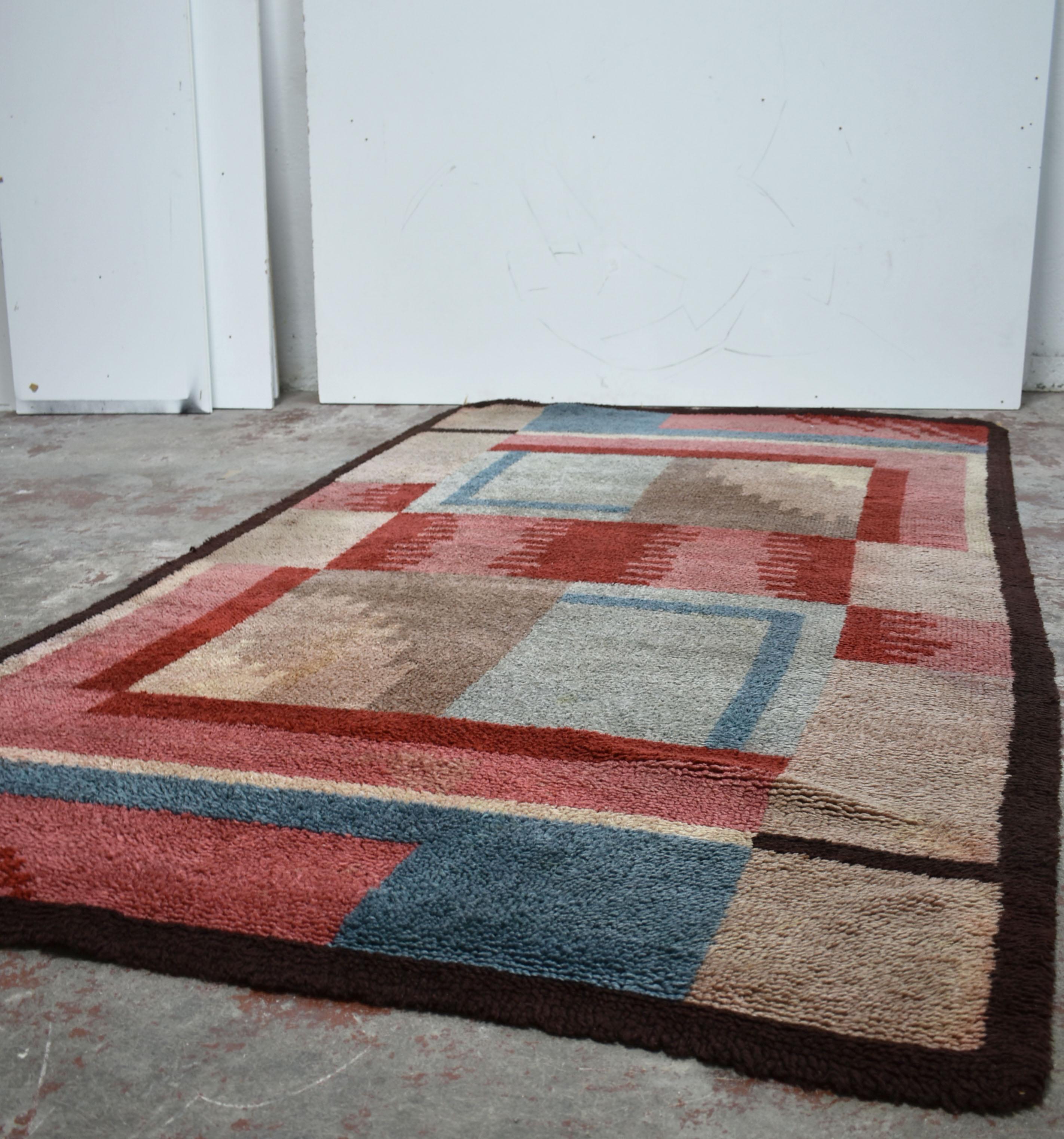 Stunning French Art Deco handwoven rug made of wool

Handcrafted in the 1930s this rug features a geometric design in De Stijl/Bauhaus style, with the colour palette consisting of shades of red, blue and tan colour framed with dark brown geometric