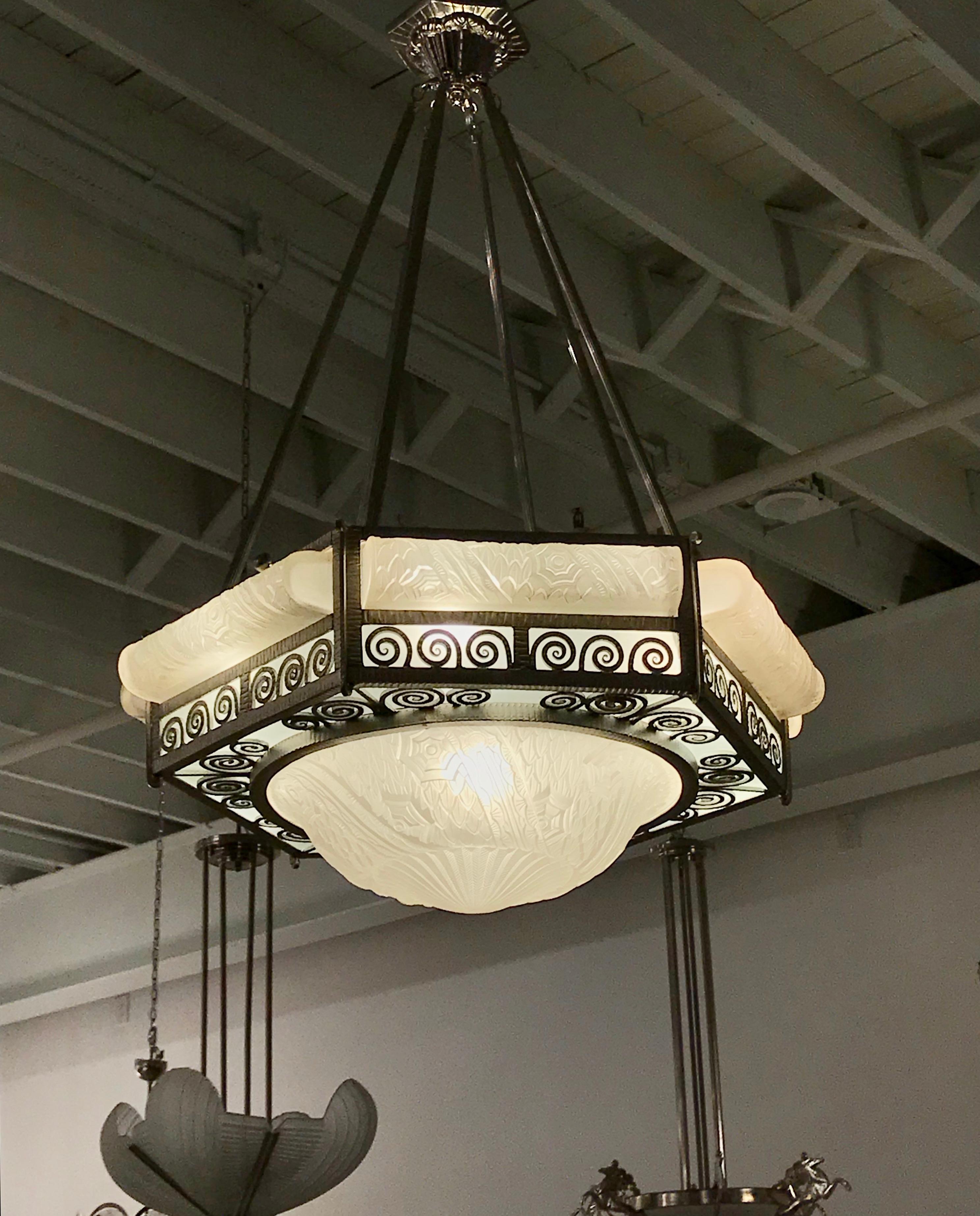 Grand French Art Deco chandelier by the French Artist Charles Schneider. With a hexagon shaped nickel bronze frame, embracing six horizontal oblong glass shades with matching central coupe. The glass shades are in clear frosted with polish details