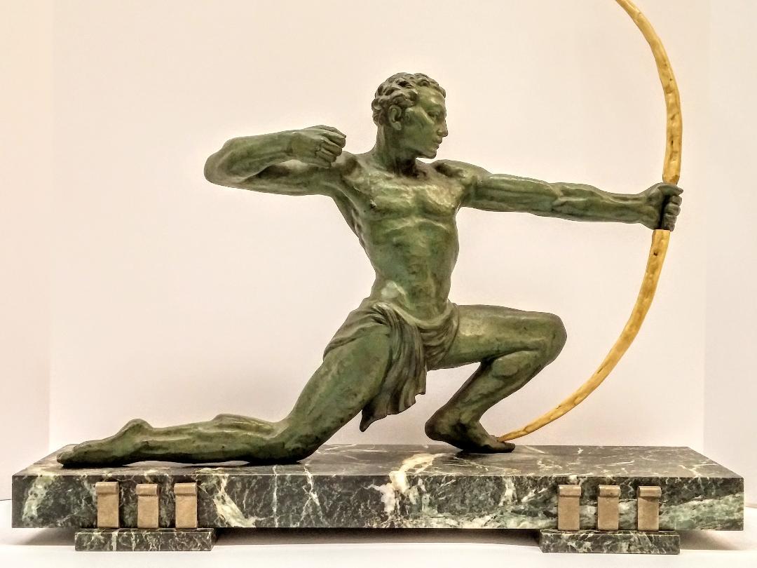 
French Art Deco hunter with a bow in a green patina in perfect condition. The sculpture rests on a green with white veined marble base with scroll metal details. We are the rare source that specializes exclusively in French Art Deco for over two