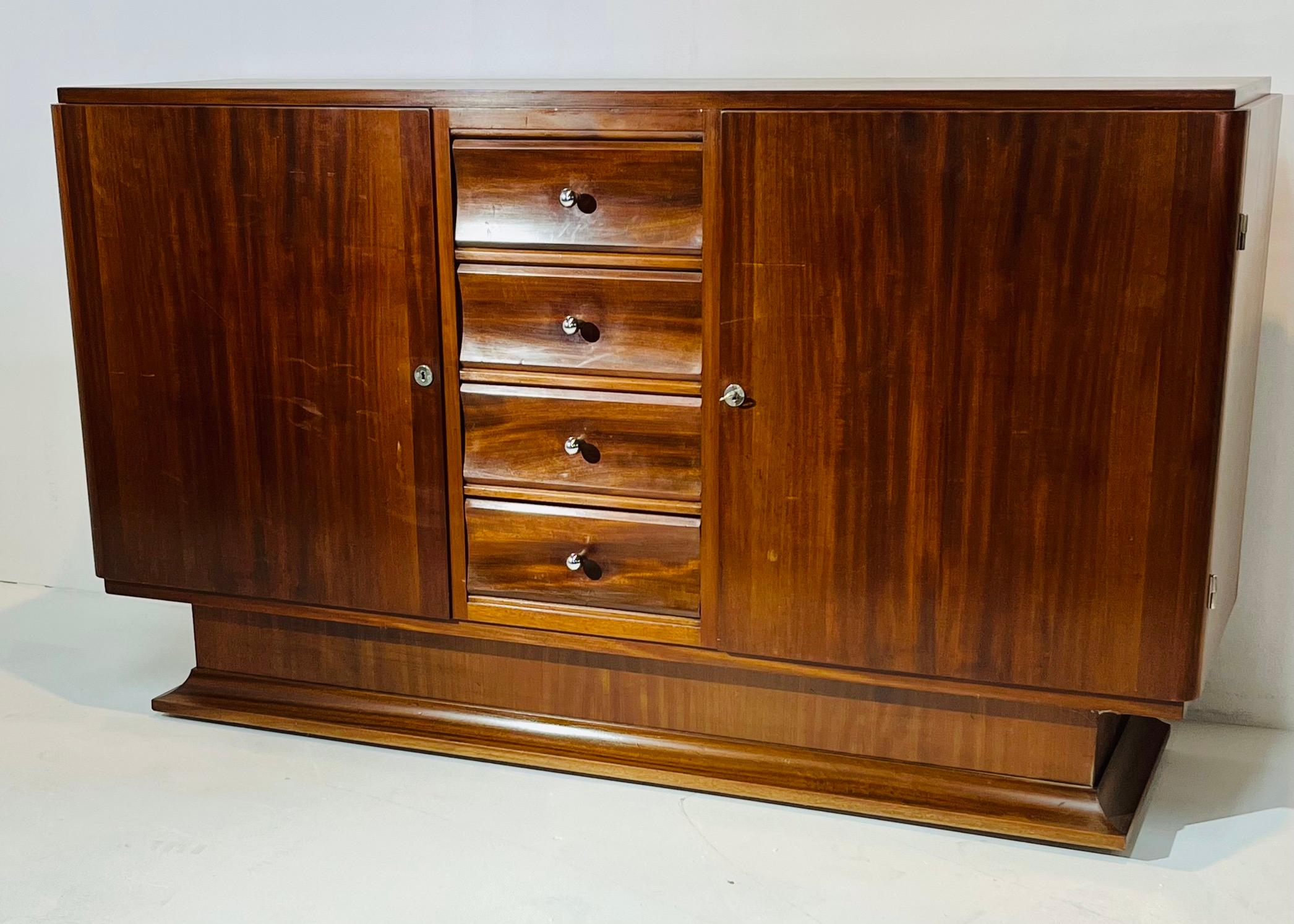 Well balanced design for this side board in solid mahogany with four drawers in the center ( the four handles have been changed ).
The piece is standing on an elegant base.
Two side doors opening on shelves.
Interesting size and design to fit in